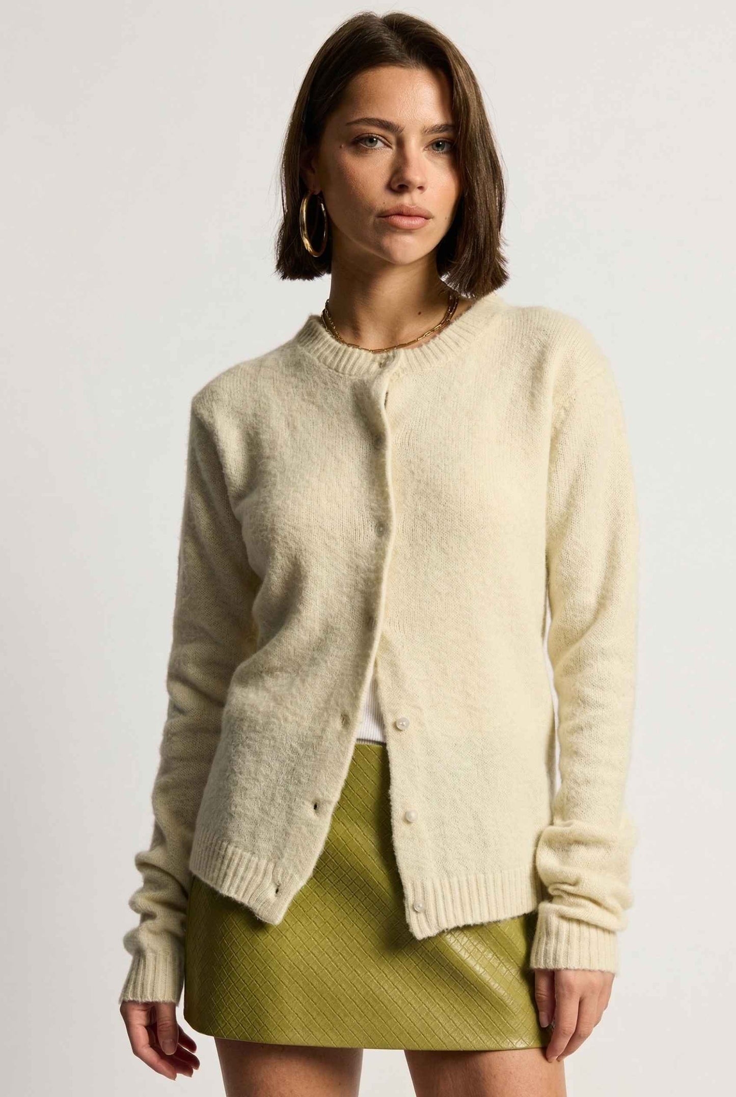 Model wearing Penelope Top in Yellow Soft Wool-Blend Crew Neck Button-Up Cardigan with leather mini skirt