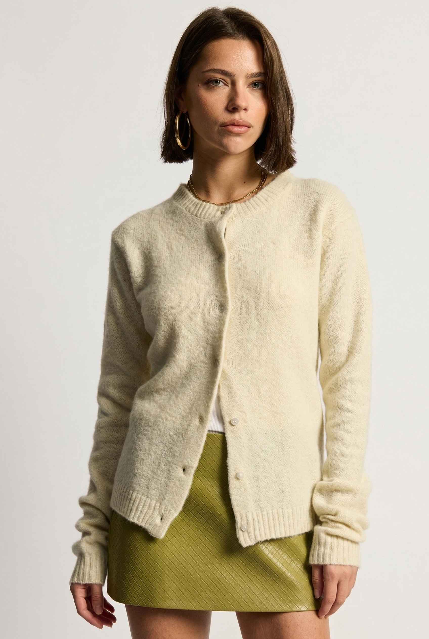 Model wearing Penelope Top in Yellow Soft Wool-Blend Crew Neck Button-Up Cardigan with leather mini skirt