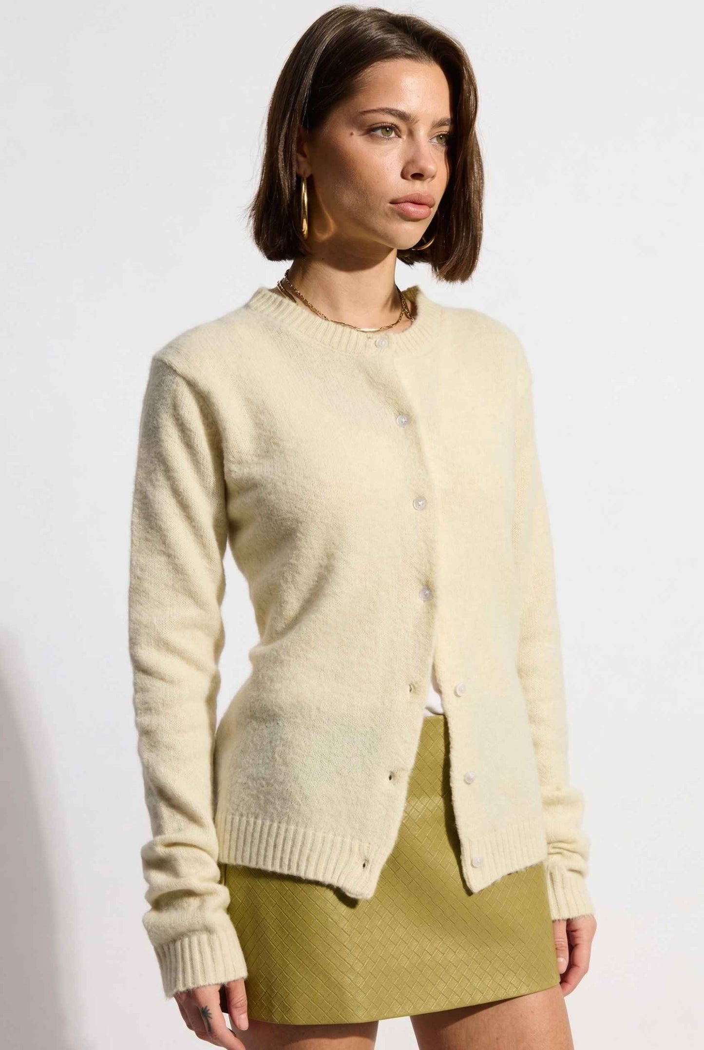 Model wearing Penelope Top in Yellow Soft Wool-Blend Crew Neck Button-Up Cardigan with leather mini skirt