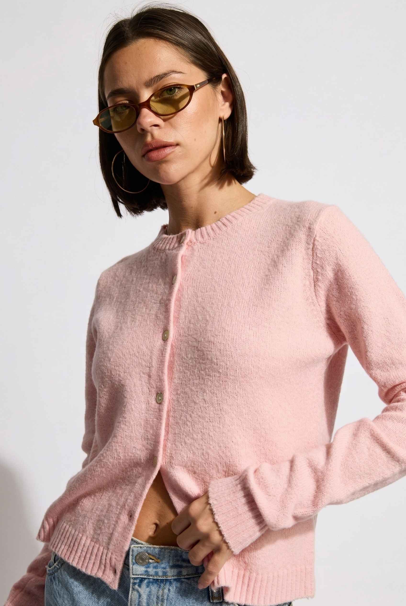 Model wearing Penelope Top in Pink Soft Wool-Blend Crew Neck Button-Up Cardigan with denim shorts 