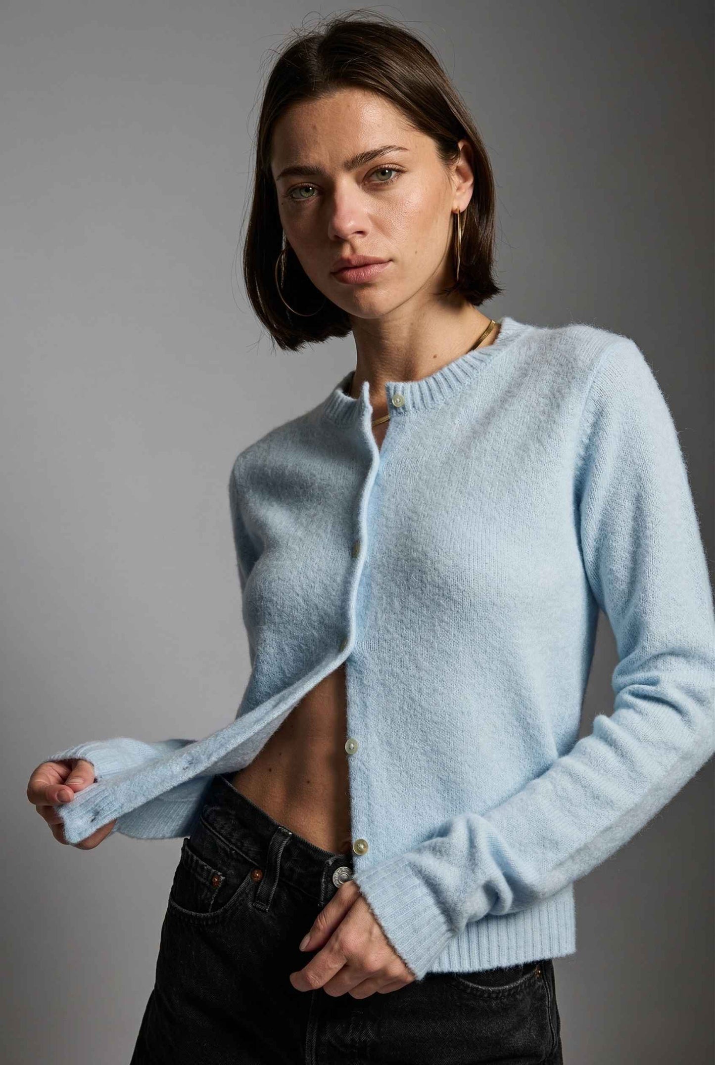Model wearing Penelope Top in Blue Soft Wool-Blend Crew Neck Button-Up Cardigan with ripped jean shorts