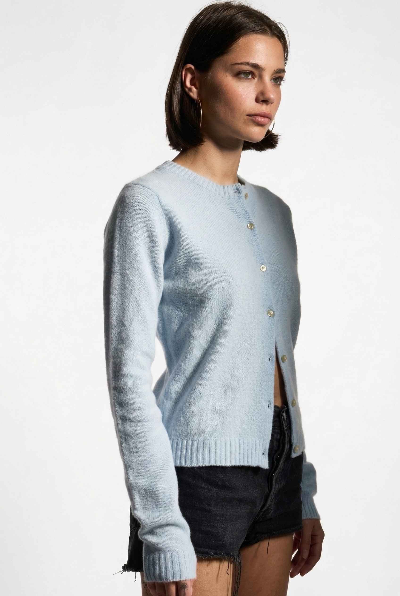 Model wearing Penelope Top in Blue Soft Wool-Blend Crew Neck Button-Up Cardigan with ripped jean shorts