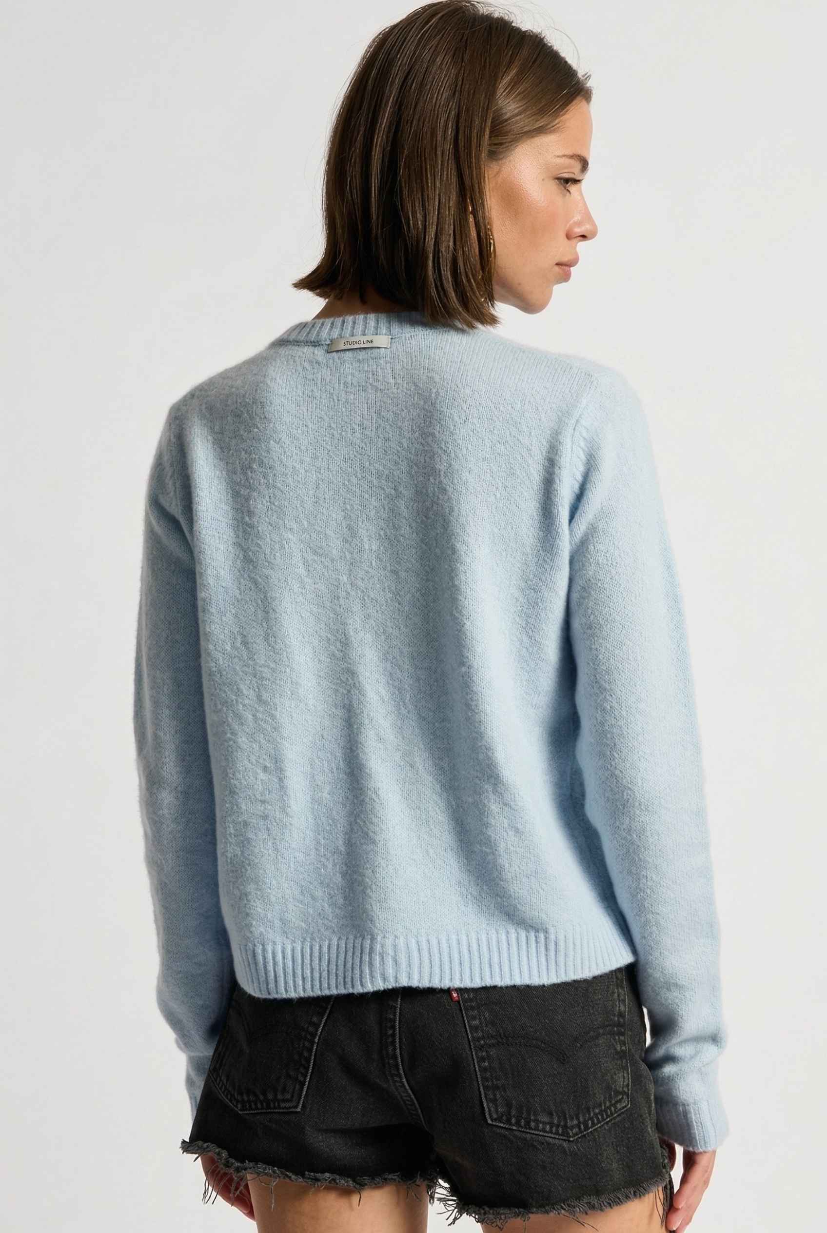 Model wearing Penelope Top in Blue Soft Wool-Blend Crew Neck Button-Up Cardigan with ripped jean shorts