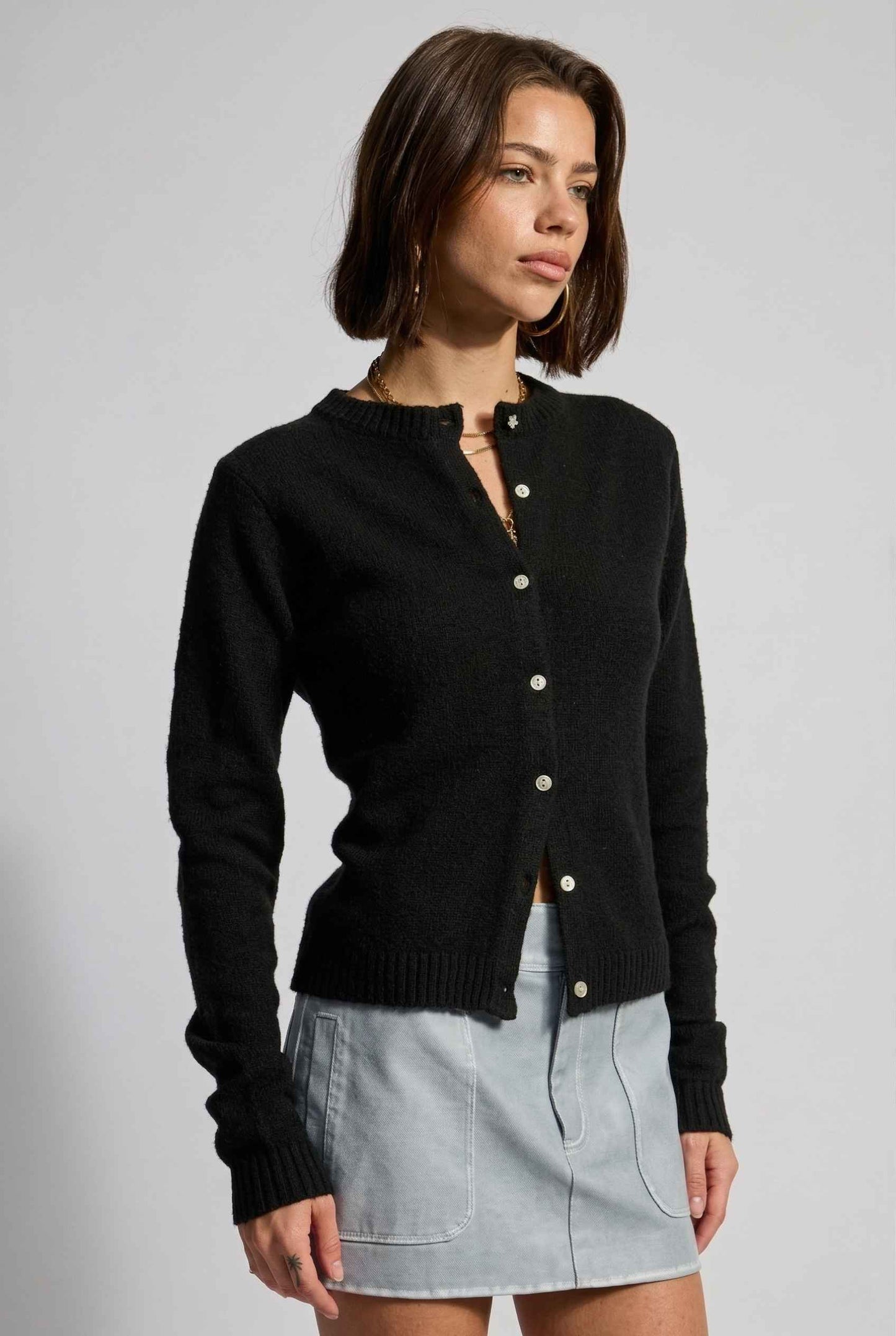 Model wearing Penelope Top in Black Soft Wool-Blend Crew Neck Button-Up Cardigan with cargo mini skirt 