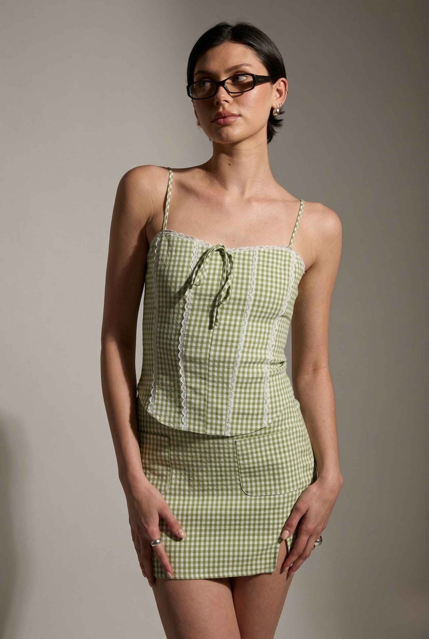 Woman wearing a Piper Top Green Gingham Lace Trim Corset Cami against a plain background