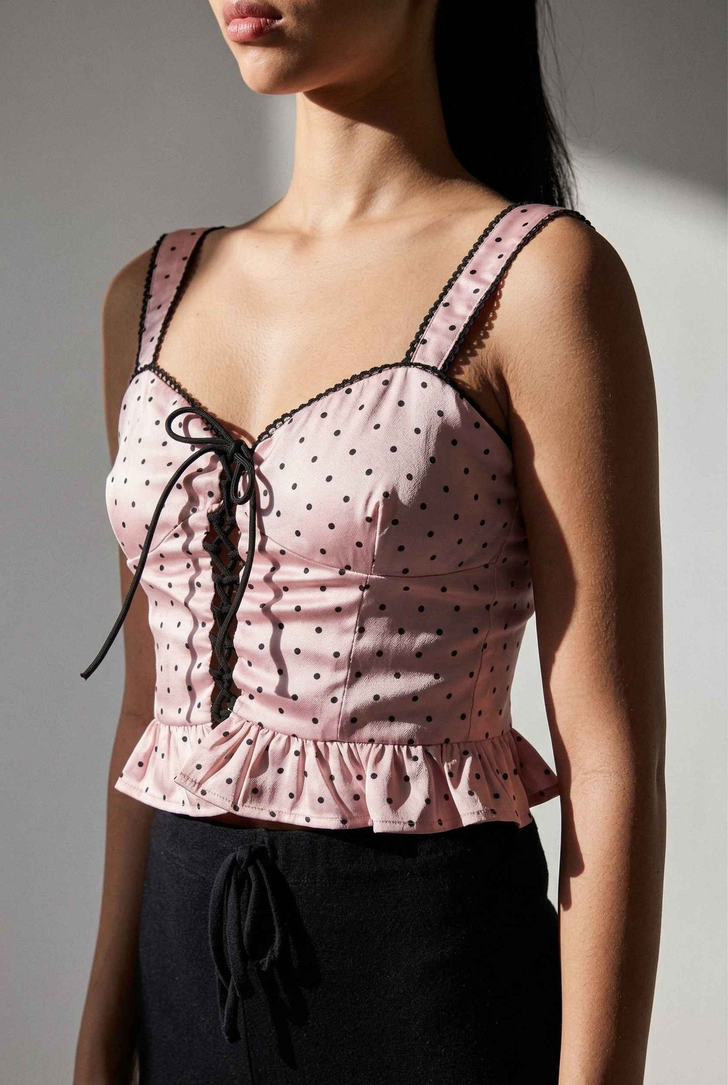 Woman wearing a Pippa Top Pink & Black Polka Dot Lace Trim Corset with lace details against a neutral background