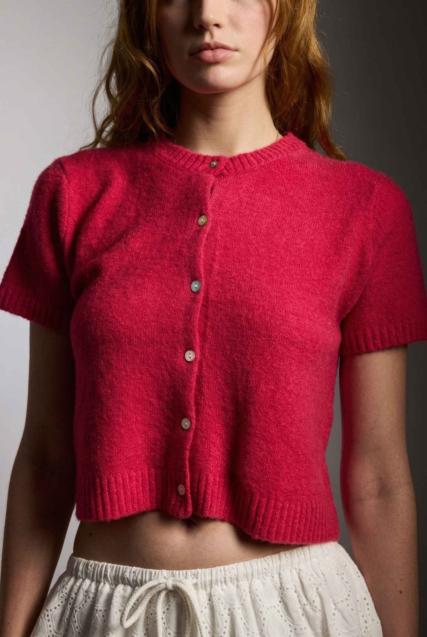 Model wearing Pippa Top in Red Short Sleeve Button-Up Cropped Cardigan paired with ruffle skirt 