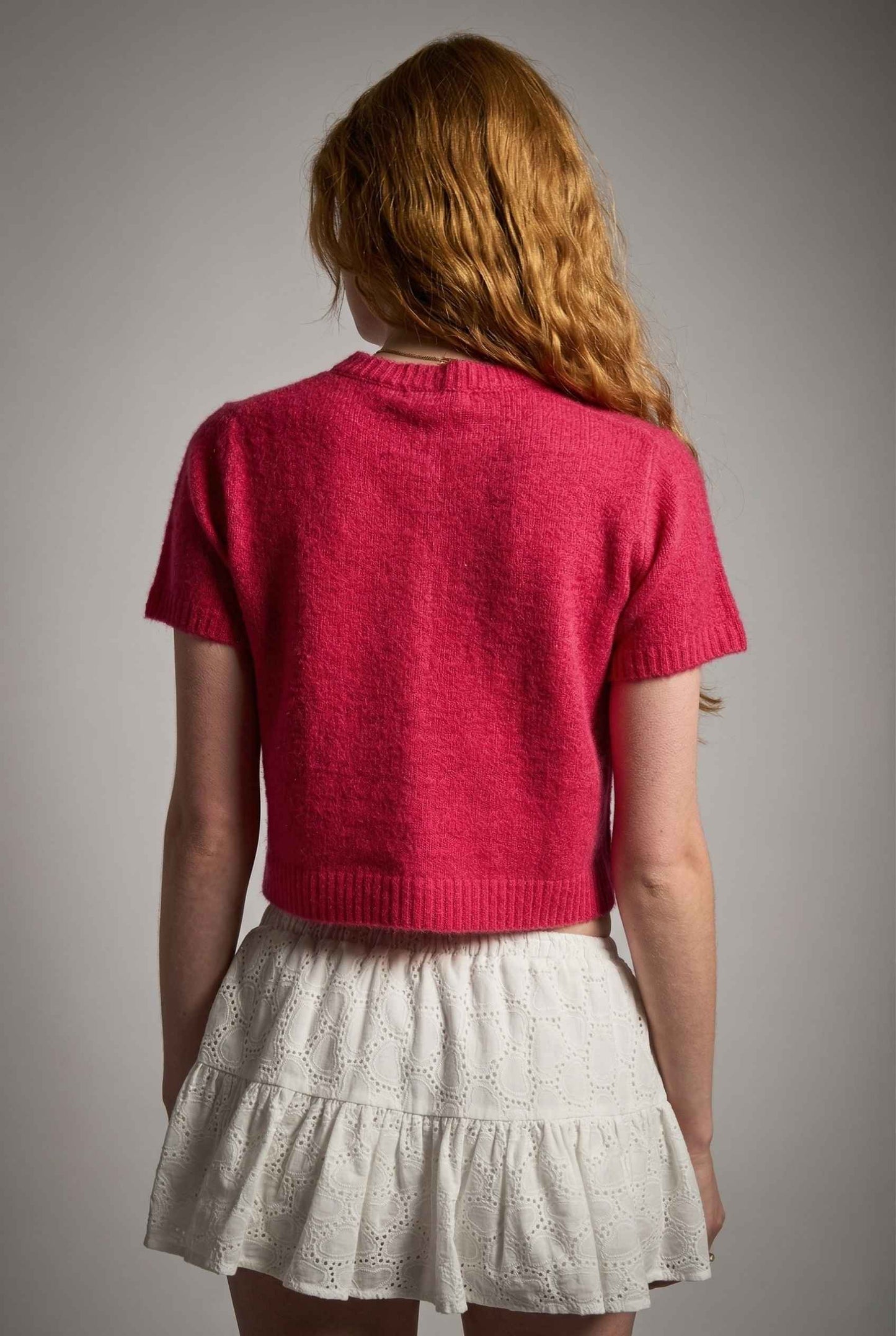 Model wearing Pippa Top in Red Short Sleeve Button-Up Cropped Cardigan paired with ruffle skirt 