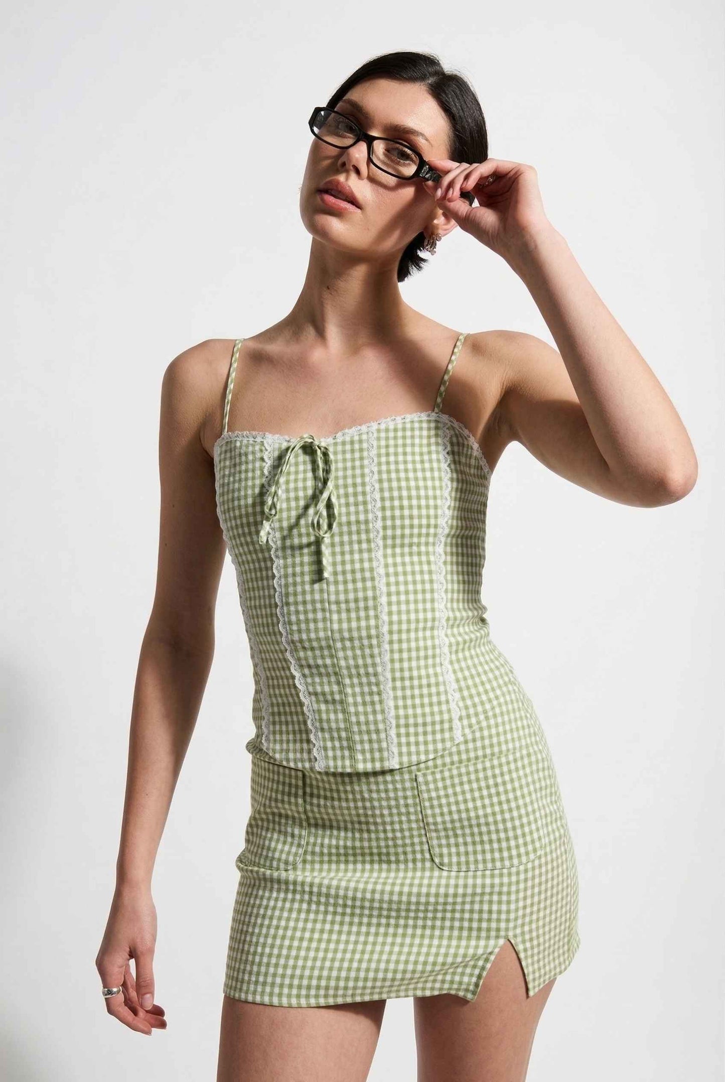 Model wearing Poppy Skirt in Sage Green Gingham Mini Skirt with Pockets paired matching corset tank top close up detail