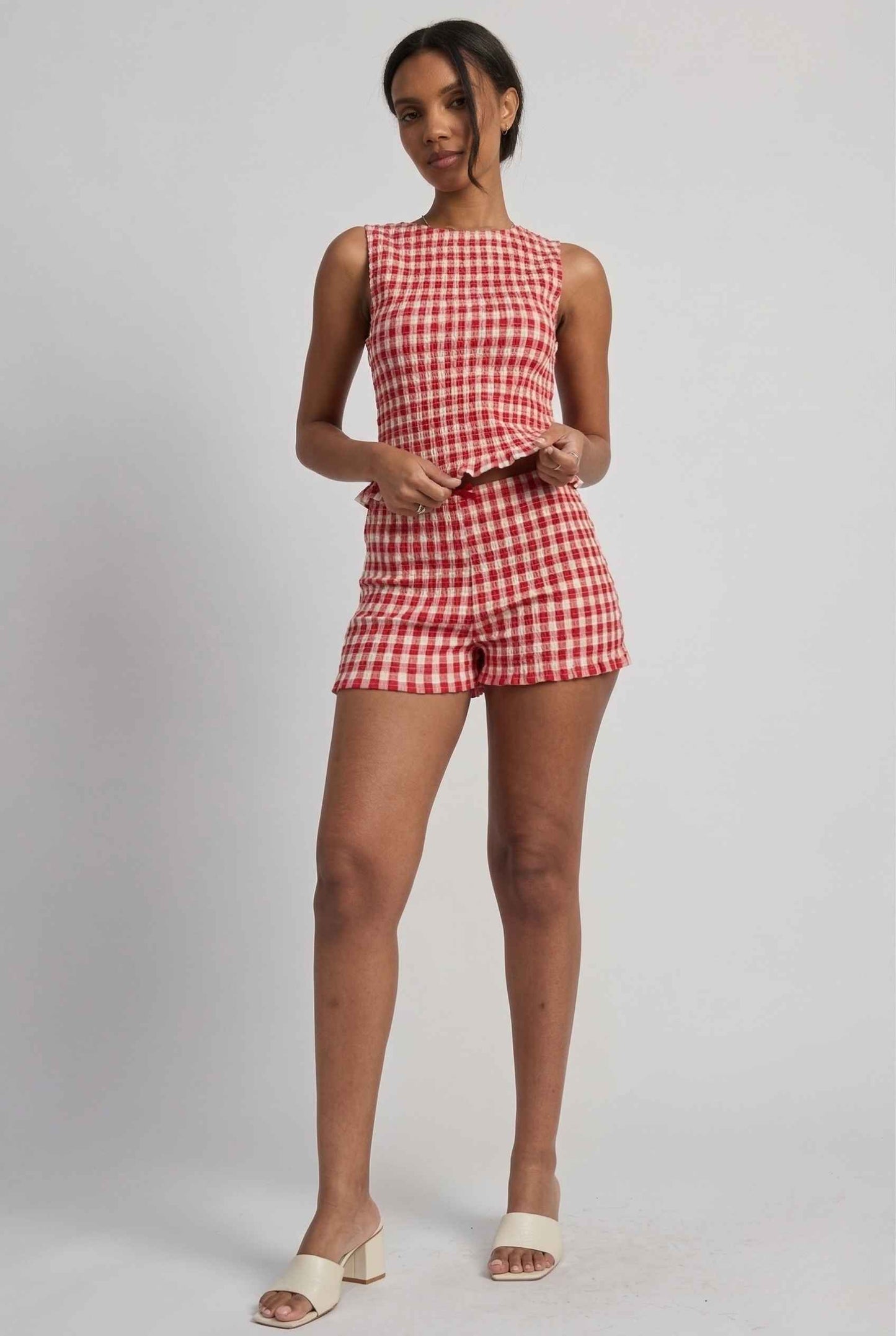 Woman wearing a rPoppy Top Red Gingham Smocked Sleeveless Knit on a plain background