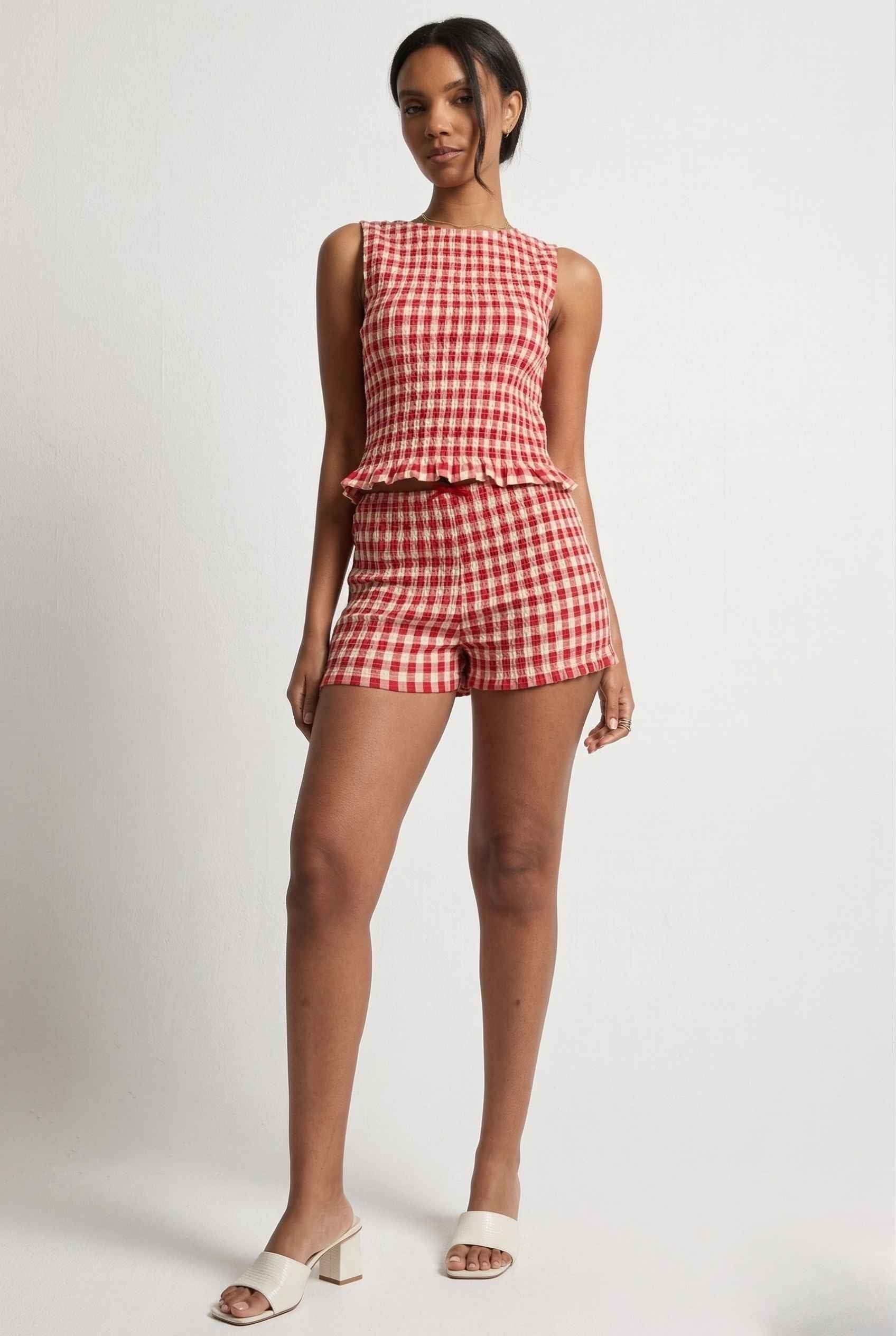 Woman wearing a rPoppy Top Red Gingham Smocked Sleeveless Knit on a plain background