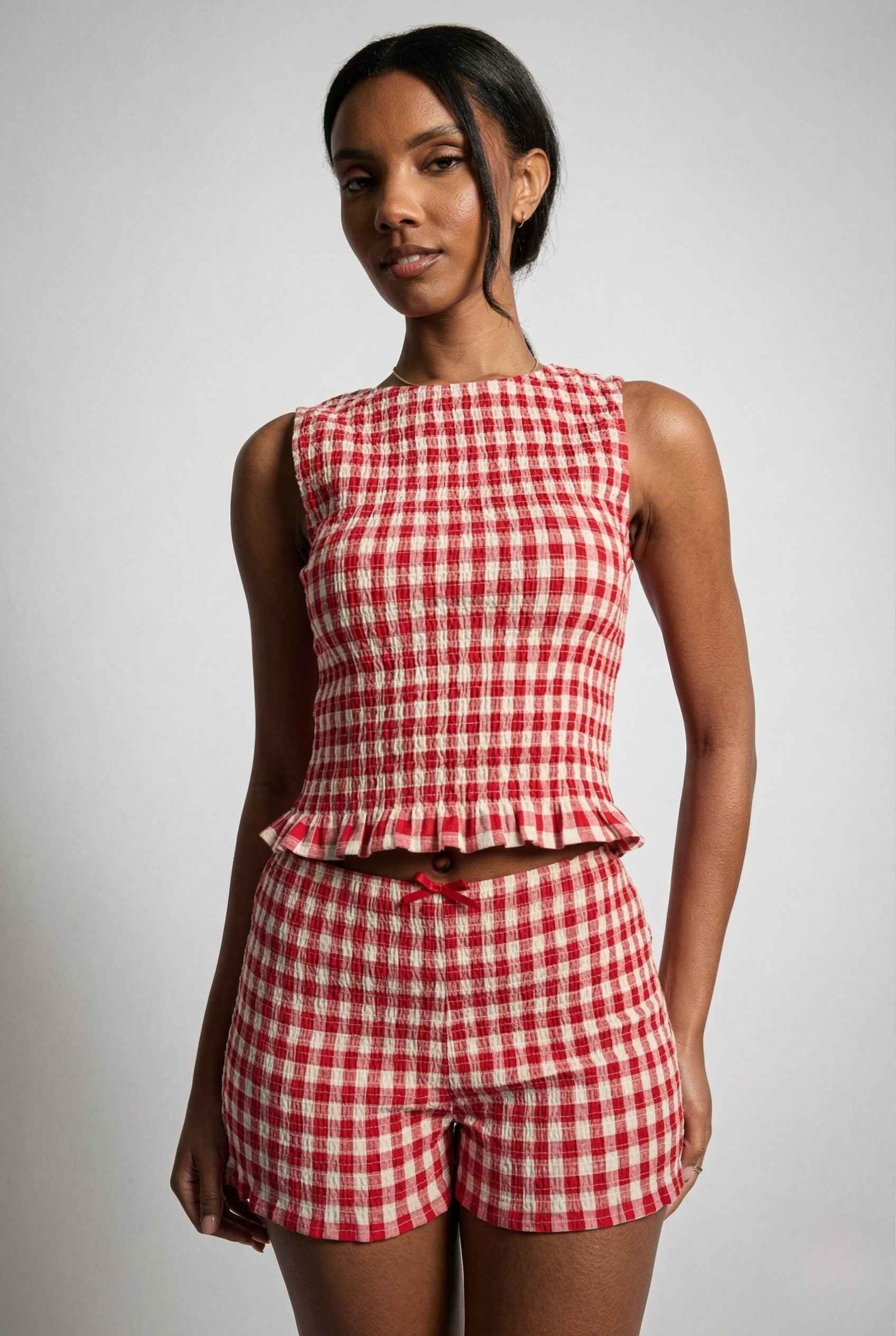 Woman wearing a Poppy Top Red Gingham Smocked Sleeveless Knit on a plain background