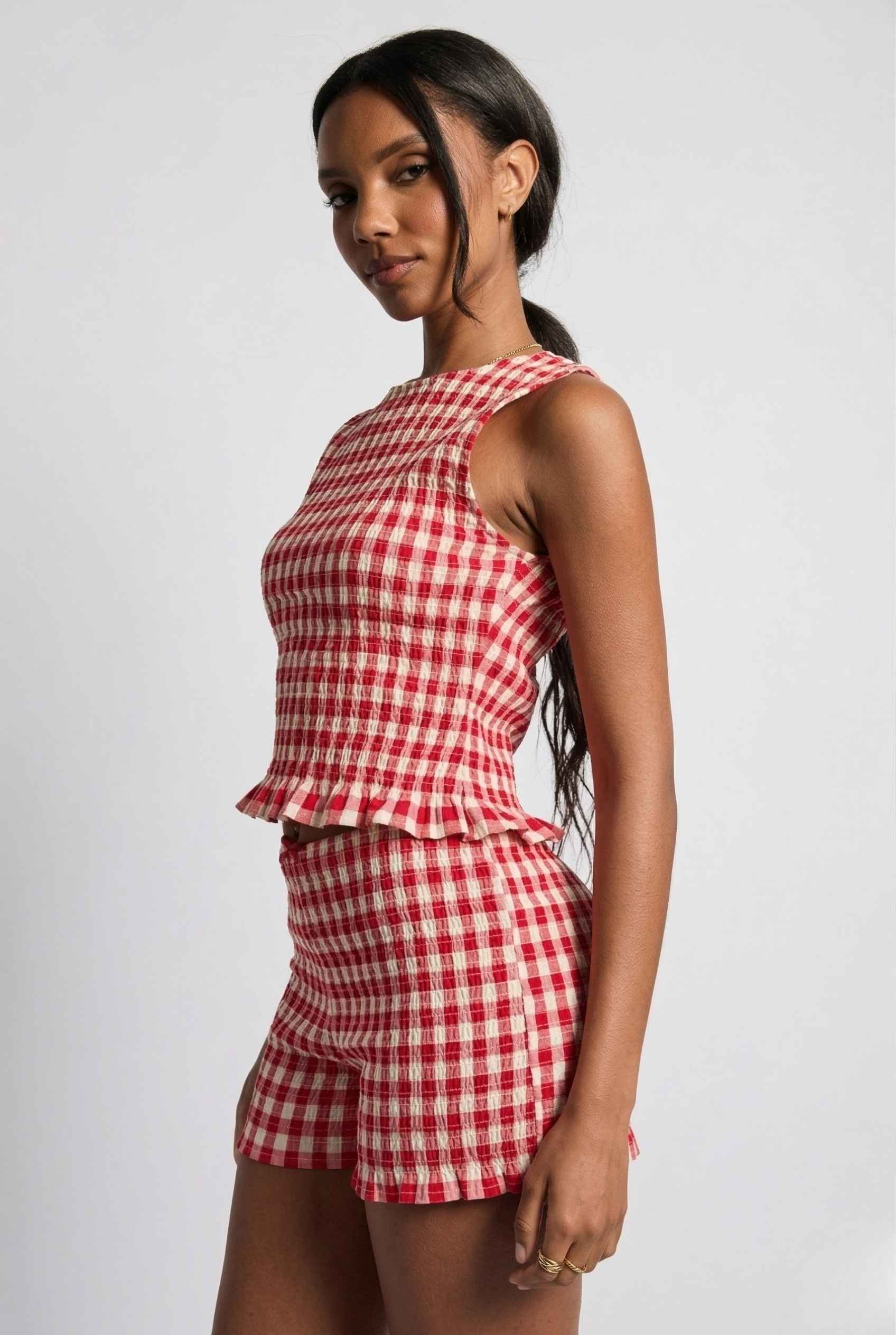 Woman wearing a rPoppy Top Red Gingham Smocked Sleeveless Knit on a plain background