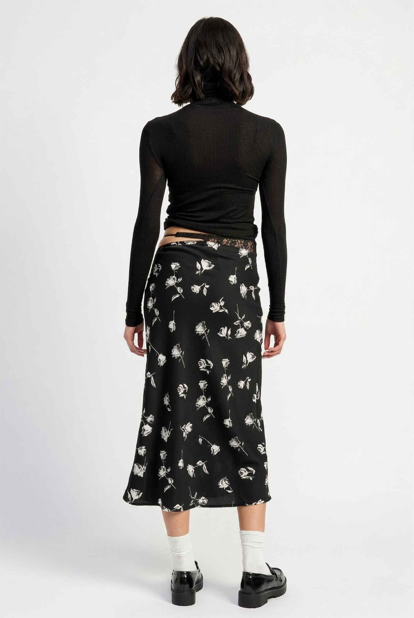 Model wearing Raven Skirt in Black Floral Satin Midi Skirt with Lace Waist paired with basic turtle neck and shiny loafers with tall socks