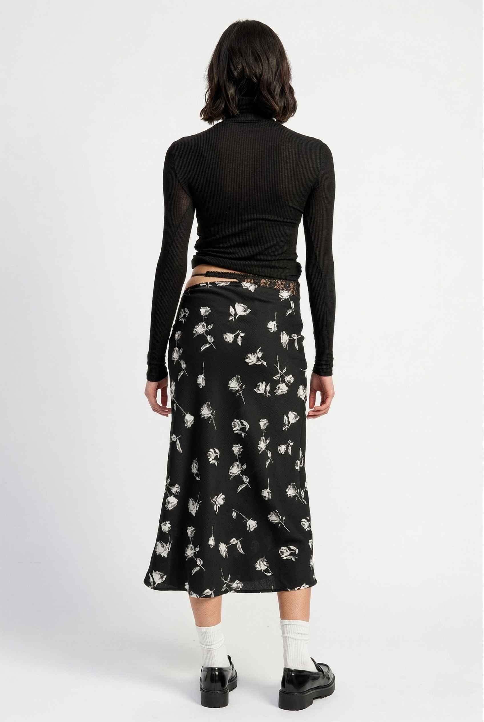 Model wearing Raven Skirt in Black Floral Satin Midi Skirt with Lace Waist paired with basic turtle neck and shiny loafers with tall socks