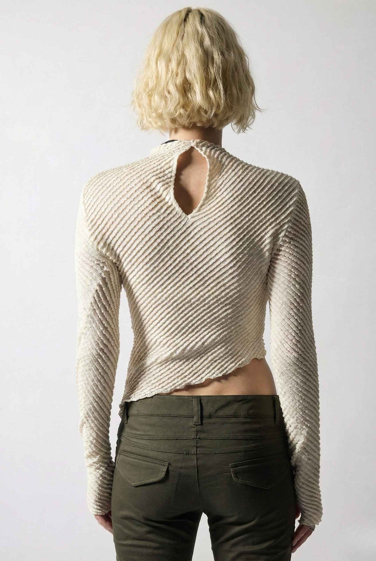 Person wearing a Ren Top Cream Asymmetrical Diagonal Rib Long Sleeve and dark pants against a white background