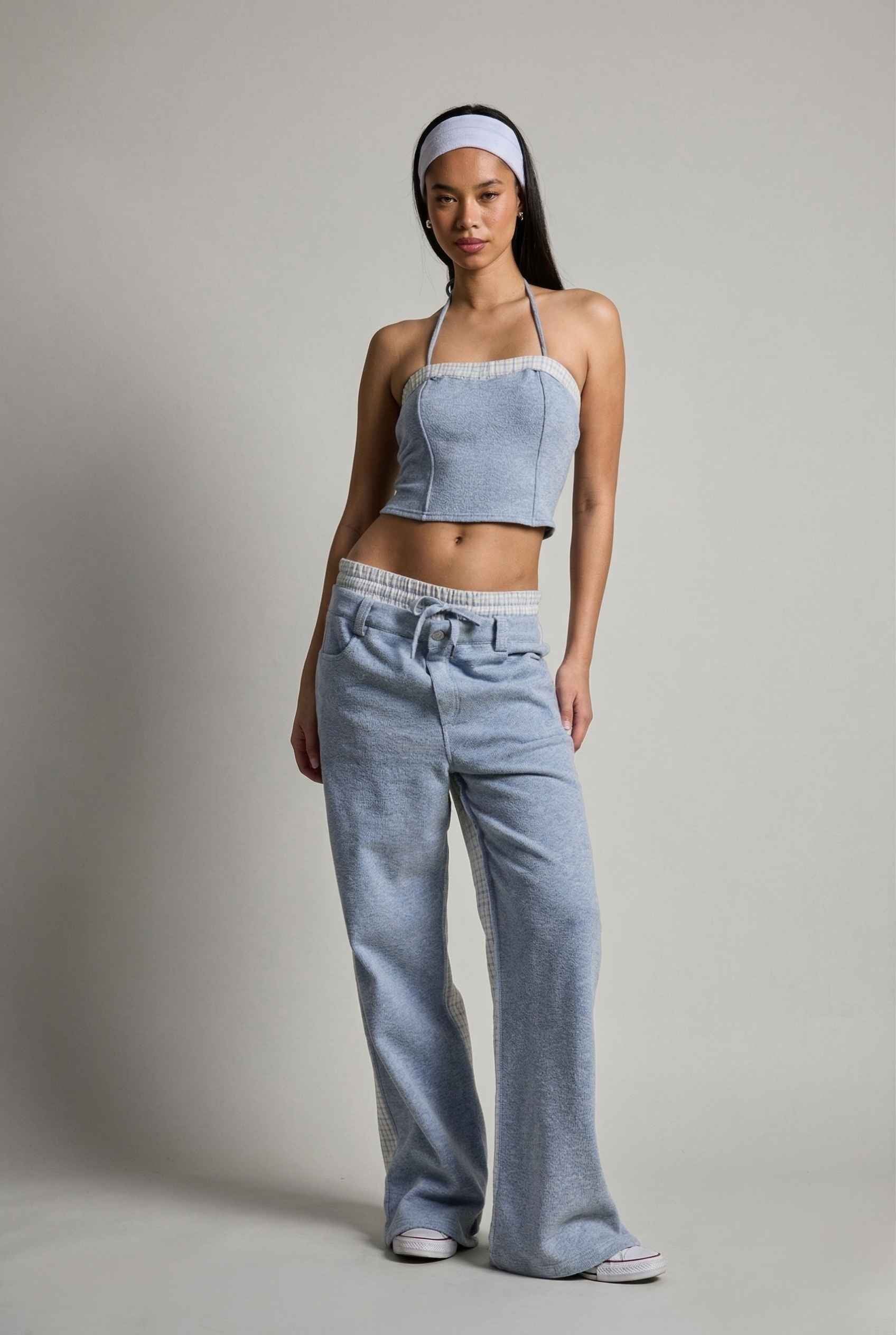 Woman wearing a Riley Top Light Blue Heathered Halter with Plaid Trim and wide-leg pants on a plain background