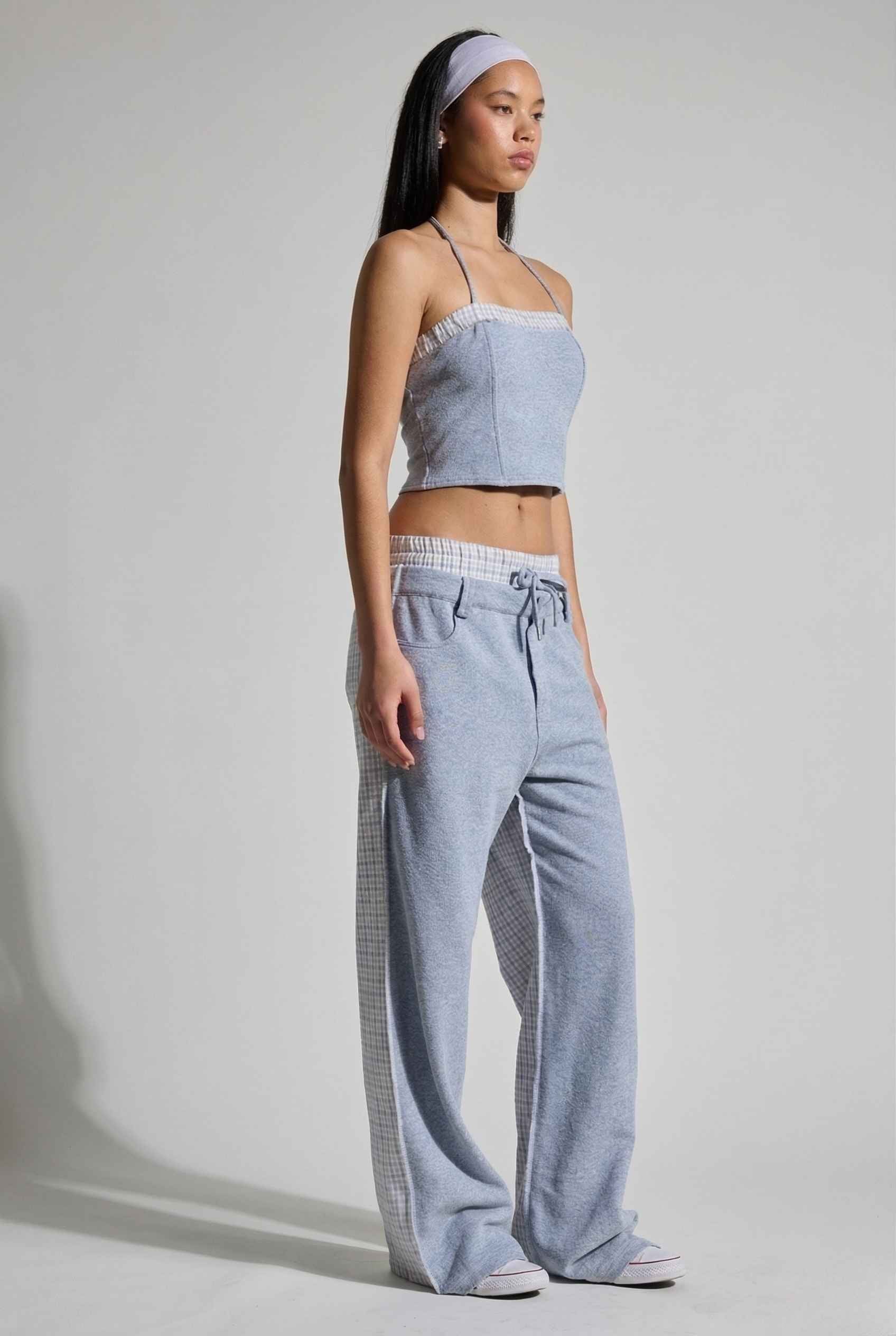 Woman wearing a Riley Top Light Blue Heathered Halter with Plaid Trim with wide-leg pants on a plain background