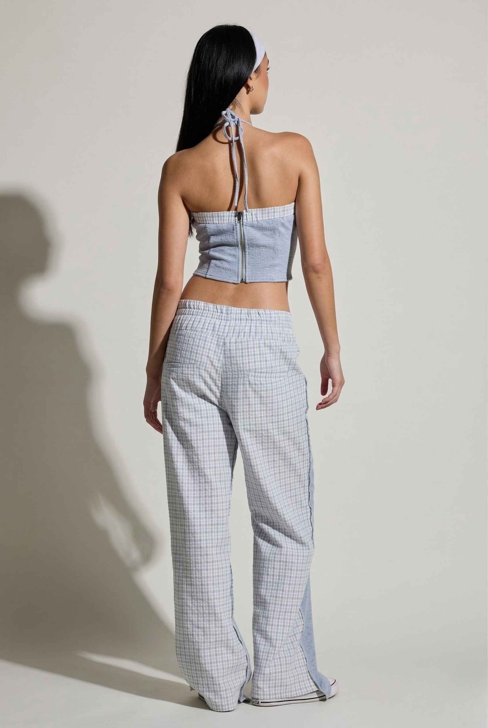 Woman wearing a Riley Top Light Blue Heathered Halter with Plaid Trim against a plain background