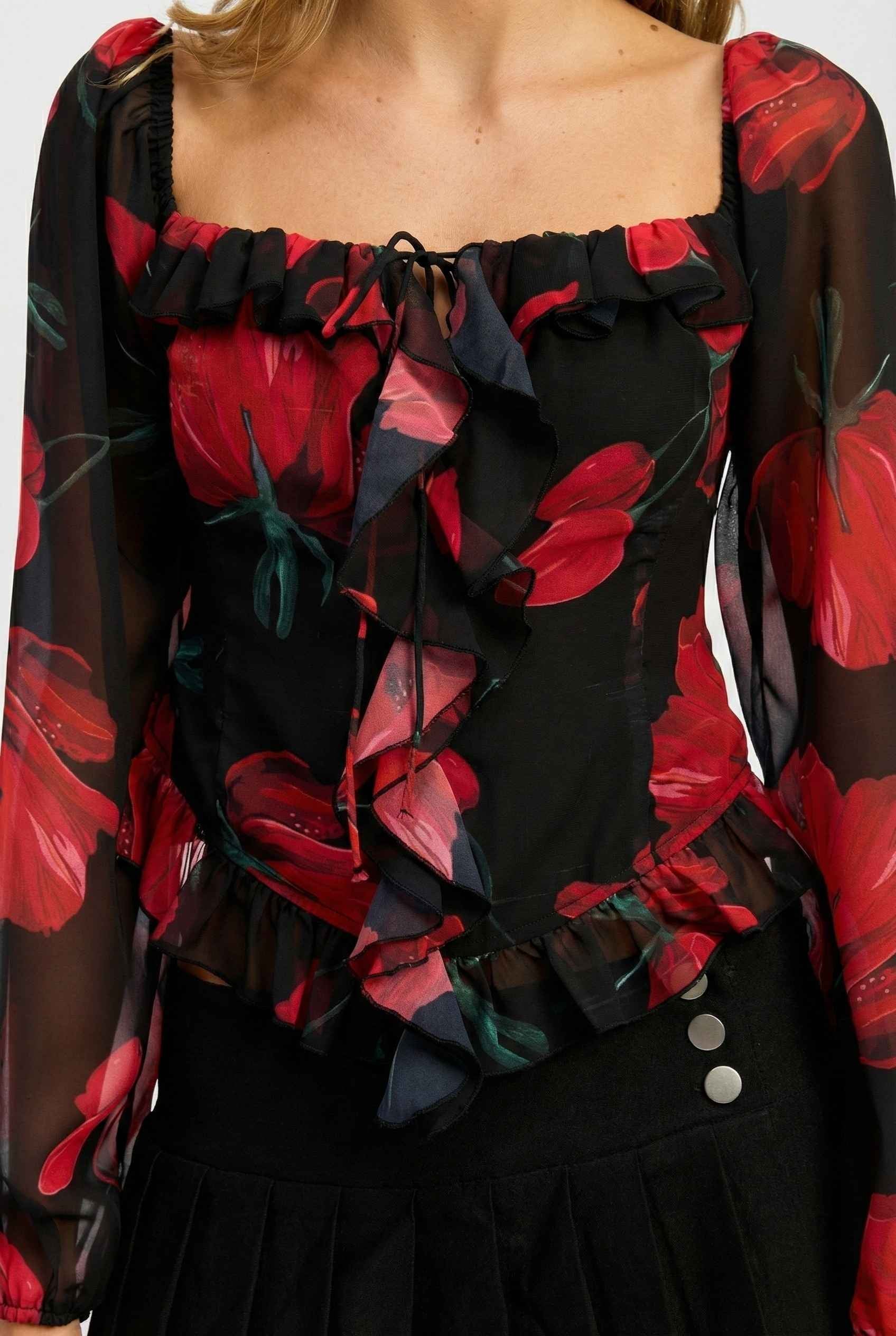 Close-up of a Rosalia Blouse Black & Red Rose Print Ruffle Top with red flowers on a black background