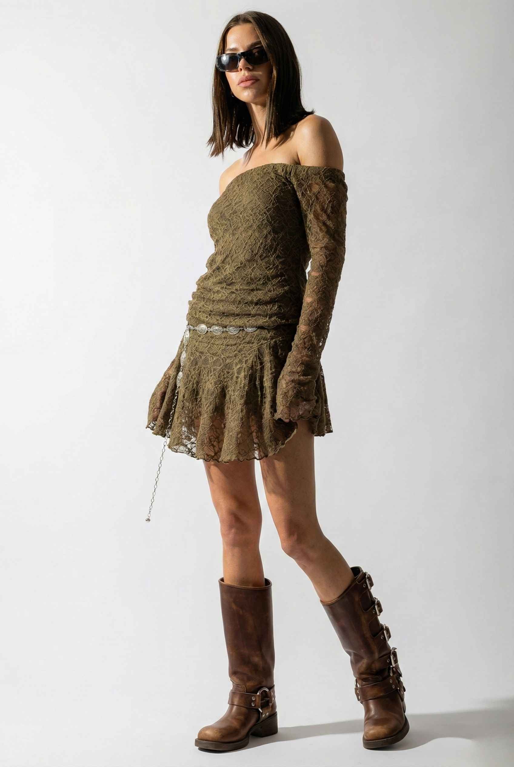 Woman wearing a Rowan Mini Olive Lace Off-Shoulder Long Sleeve Dress and brown boots against a white background