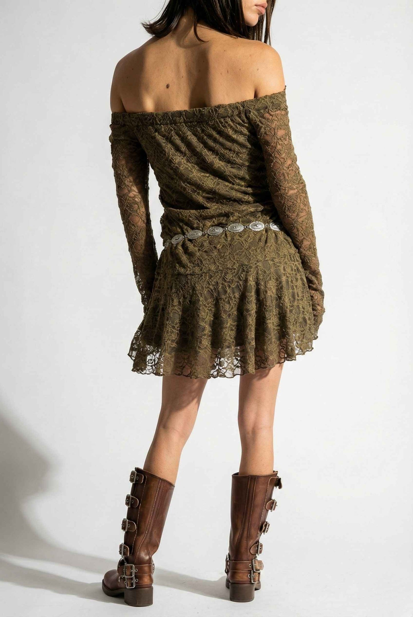Woman wearing a Rowan Mini Olive Lace Off-Shoulder Long Sleeve Dress with lace details and brown boots on a white background