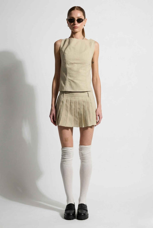 Woman wearing a Rowan Top Cream Cotton Blend Boat Neck Sleeveless Top and skirt with white knee-high socks and black shoes on a white background