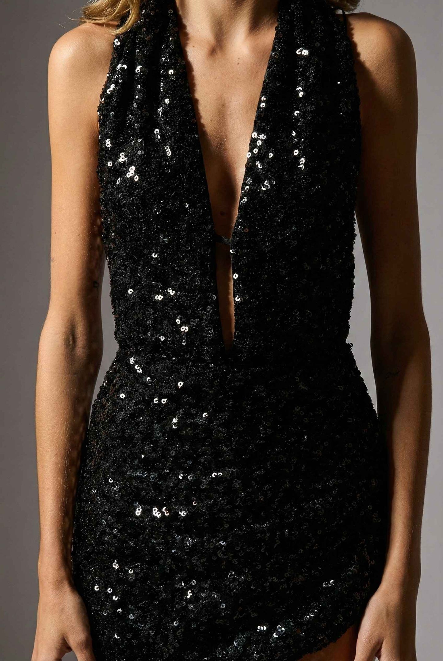 Roxy Mini Black Sequin Halter Plunge Dress with a deep neckline on a gray background