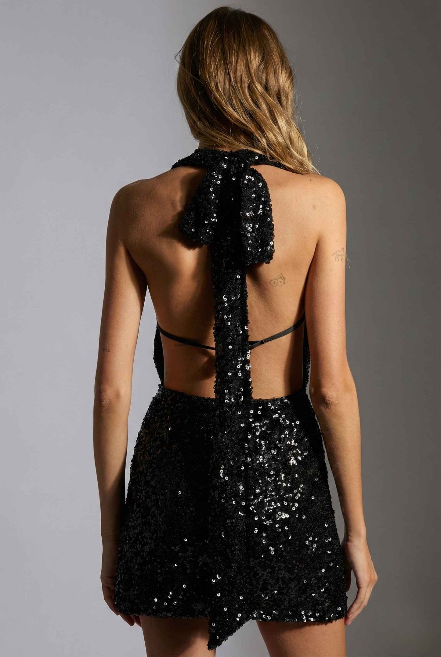 Roxy Mini Black Sequin Halter Plunge Dress with a bow detail on a plain background