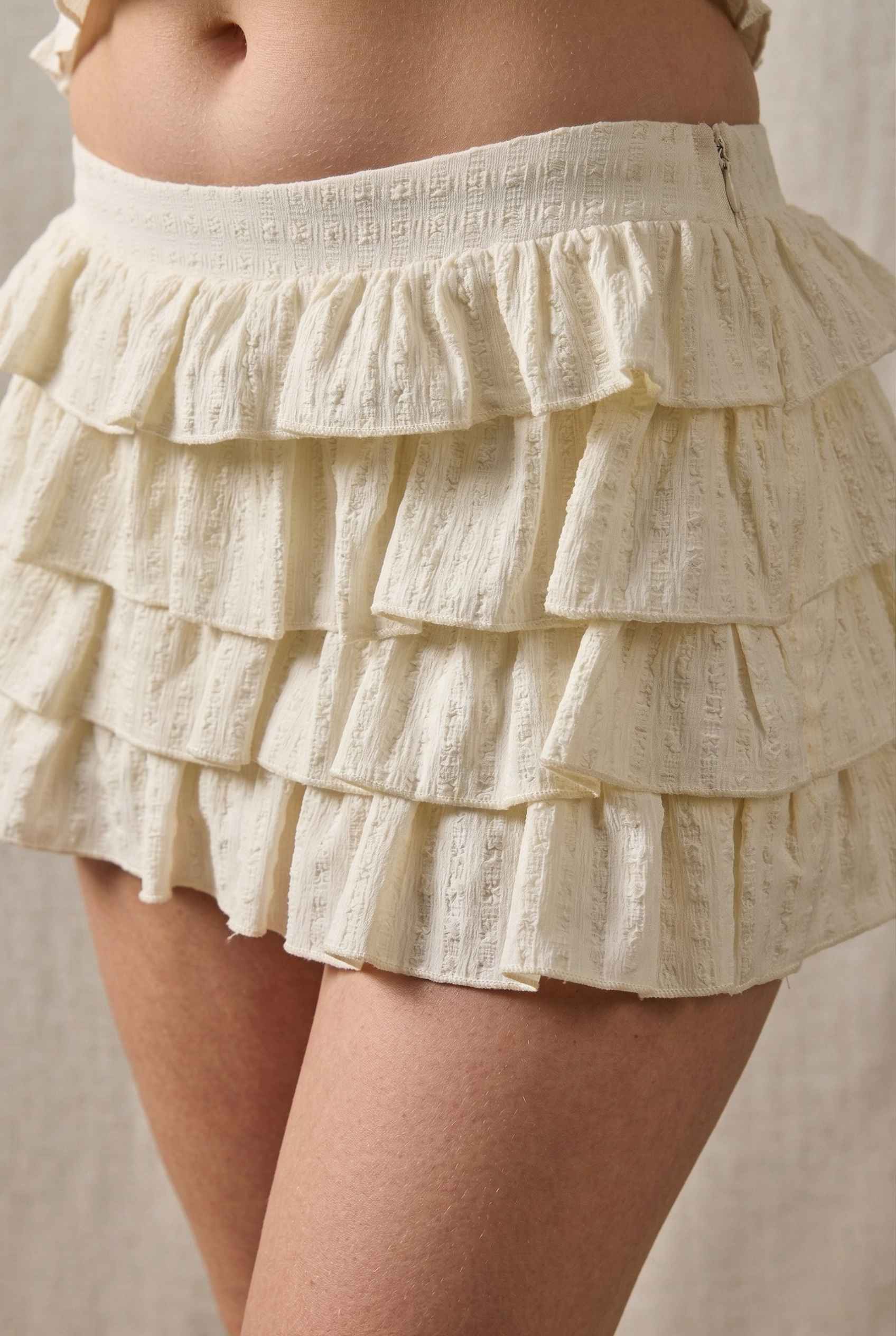 Model wearing Roxy Skirt Ruffle Ra-Ra Mini Skirt in Cream with matching tank top close up delicate ruffle detail