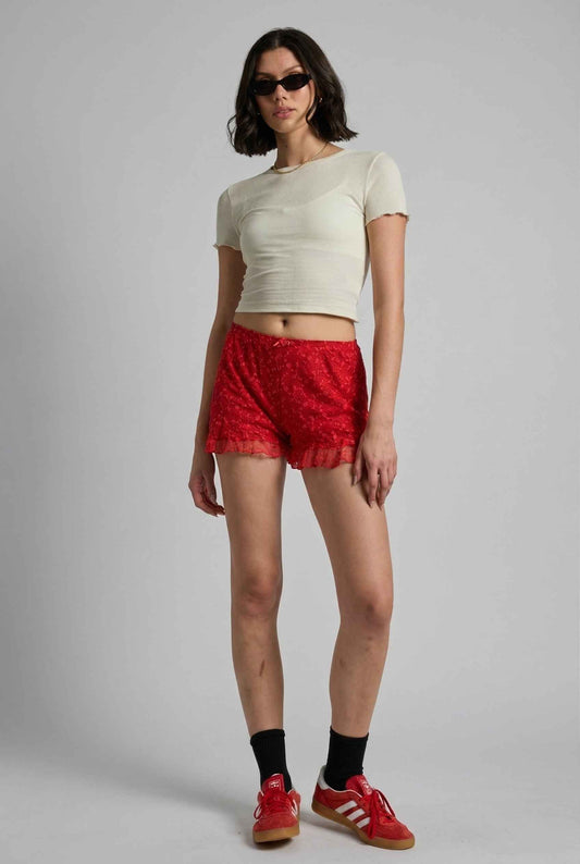 Model wearing Ruby Shorts in Red Lace Ruffle Bloomer Shorts with Bow paired with cropped t-shirt and casual sneakers with socks