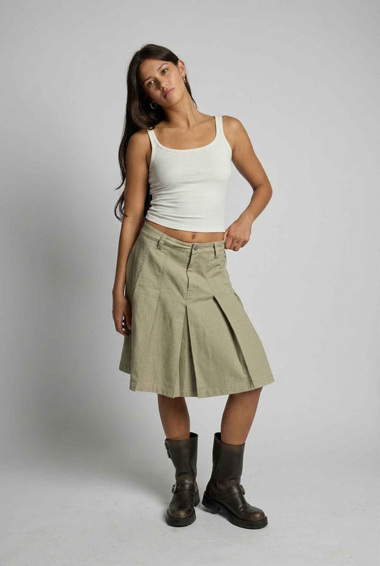 Model wearing Sawyer Skirt in Khaki Cotton Knee-Length Pleated Skirt paired with tie-neck halter top and pirate boots