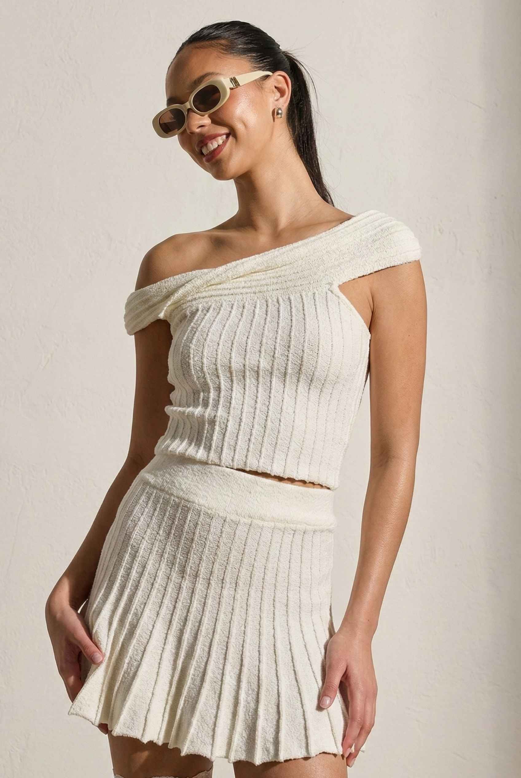 Model wearing Seraphina Top in White Ribbed Knit Twist-Front Off-Shoulder Top with matching mini skirt