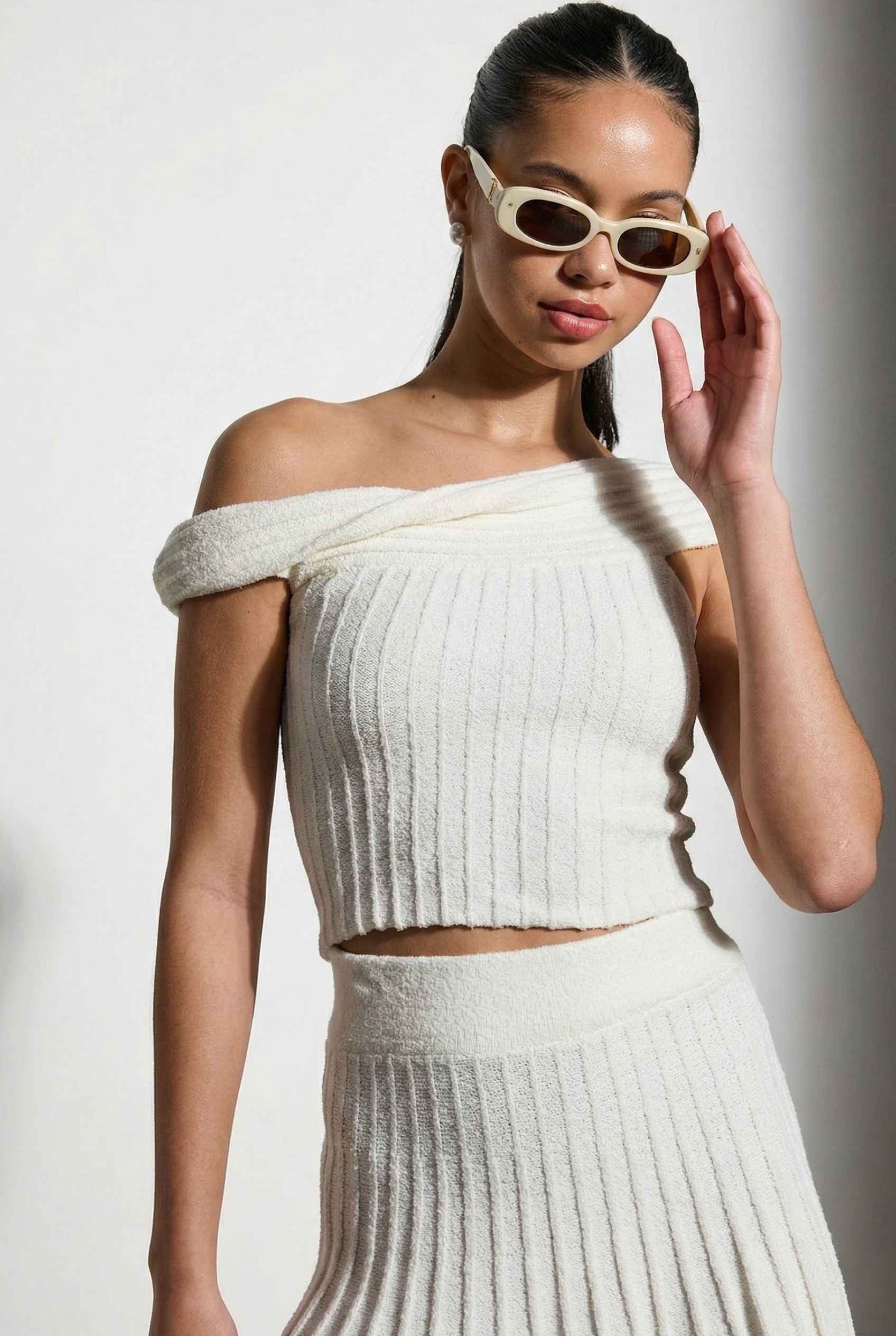 Model wearing Seraphina Top in White Ribbed Knit Twist-Front Off-Shoulder Top with matching mini skirt