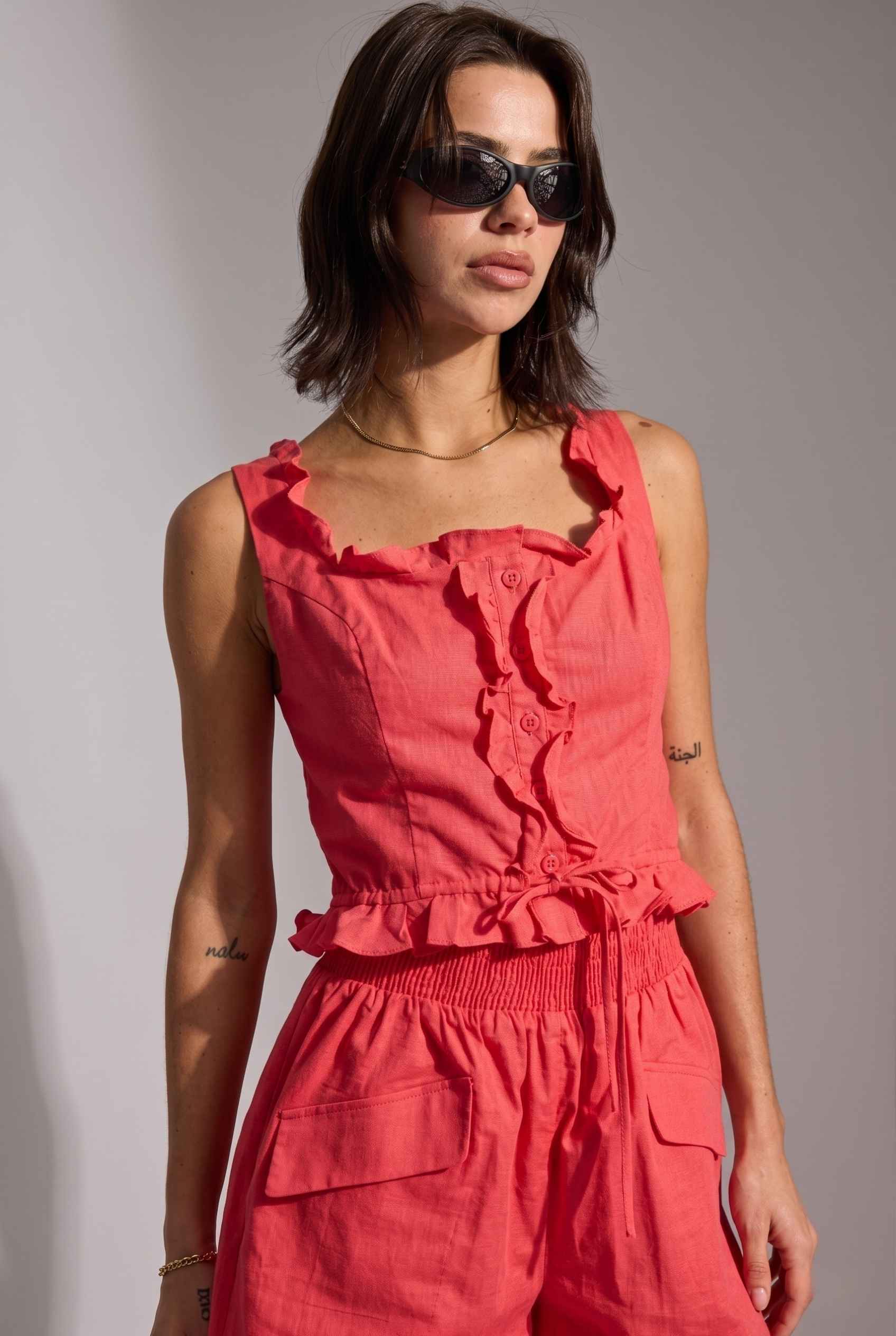 Model wearing Shay Ruffle Button-Front Top Cotton-Linen Tank Top in Red with matching smocked shorts