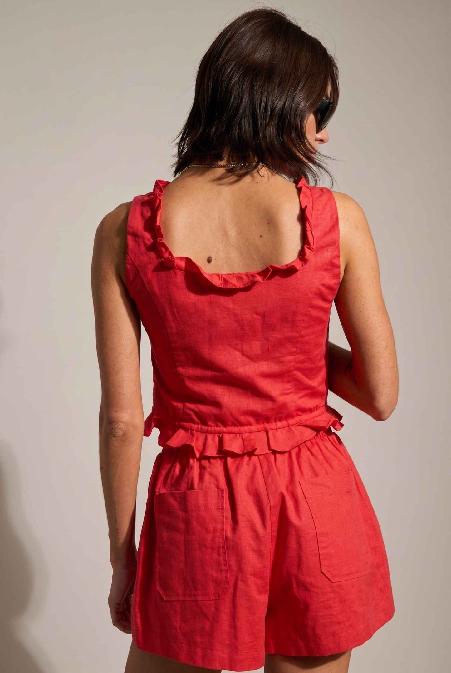 Model wearing Shay Ruffle Button-Front Top Cotton-Linen Tank Top in Red with matching smocked shorts