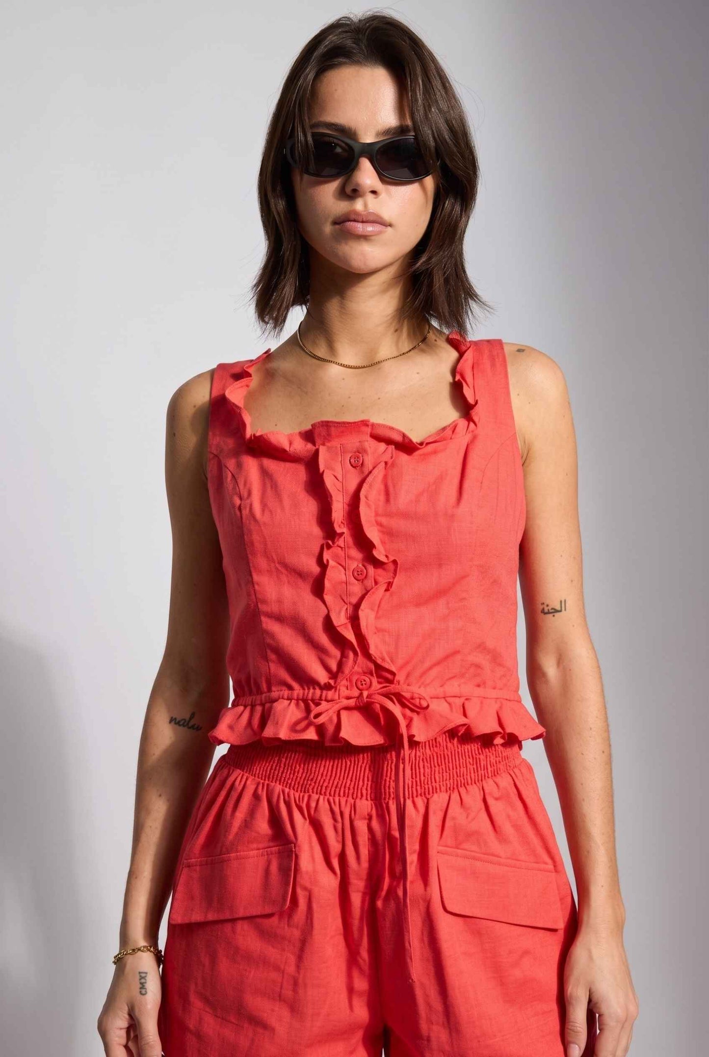 Model wearing Shay Ruffle Button-Front Top Cotton-Linen Tank Top in Red with matching smocked shorts
