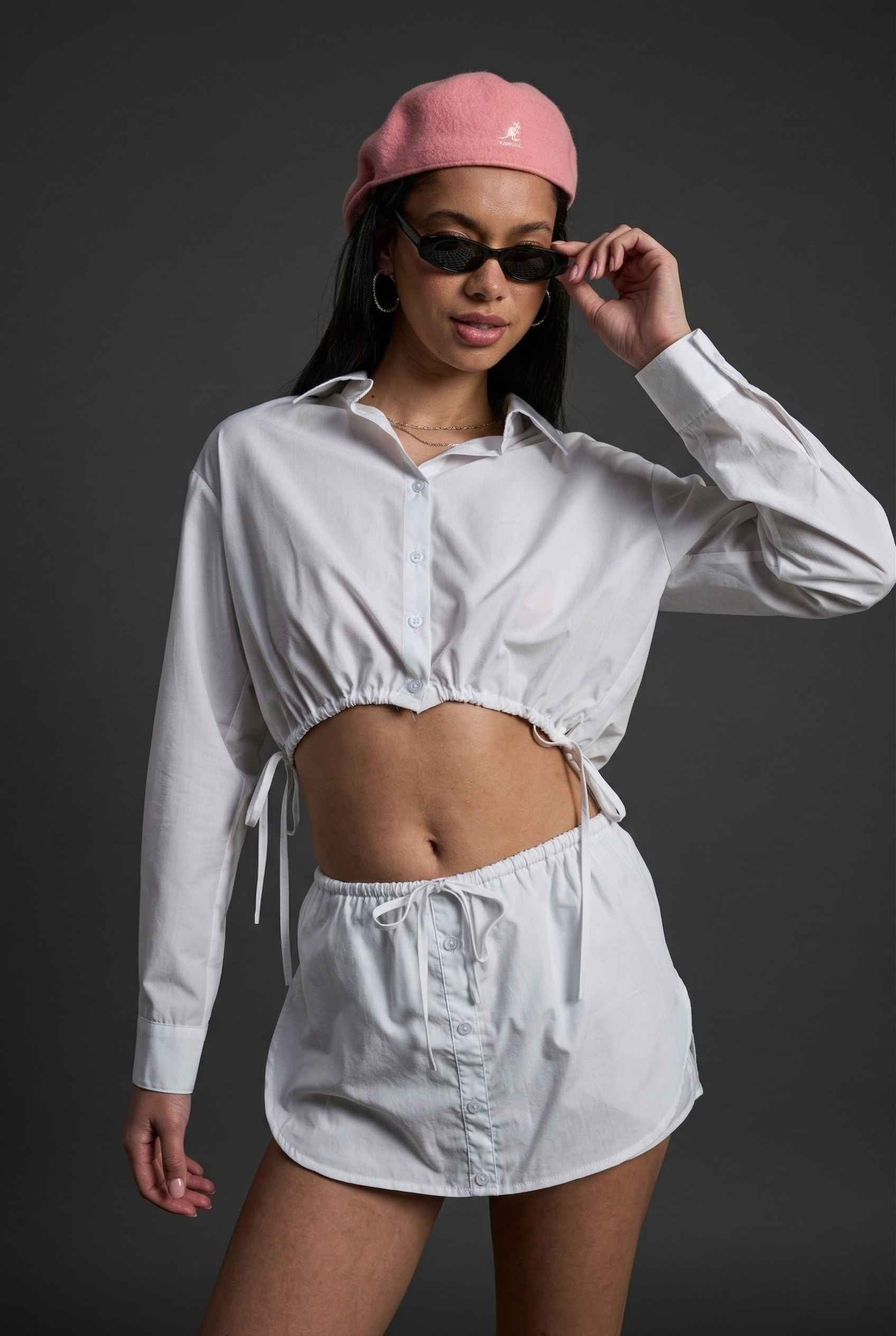 Model wearing Shea Skort in White Cotton-Blend Poplin Mini Skort with Drawstring paired with matching crop top and bistro hat