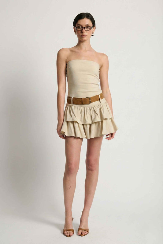 Woman wearing a Sienna Mini Beige Strapless Belted Ruffle Dress with a brown belt on a white background