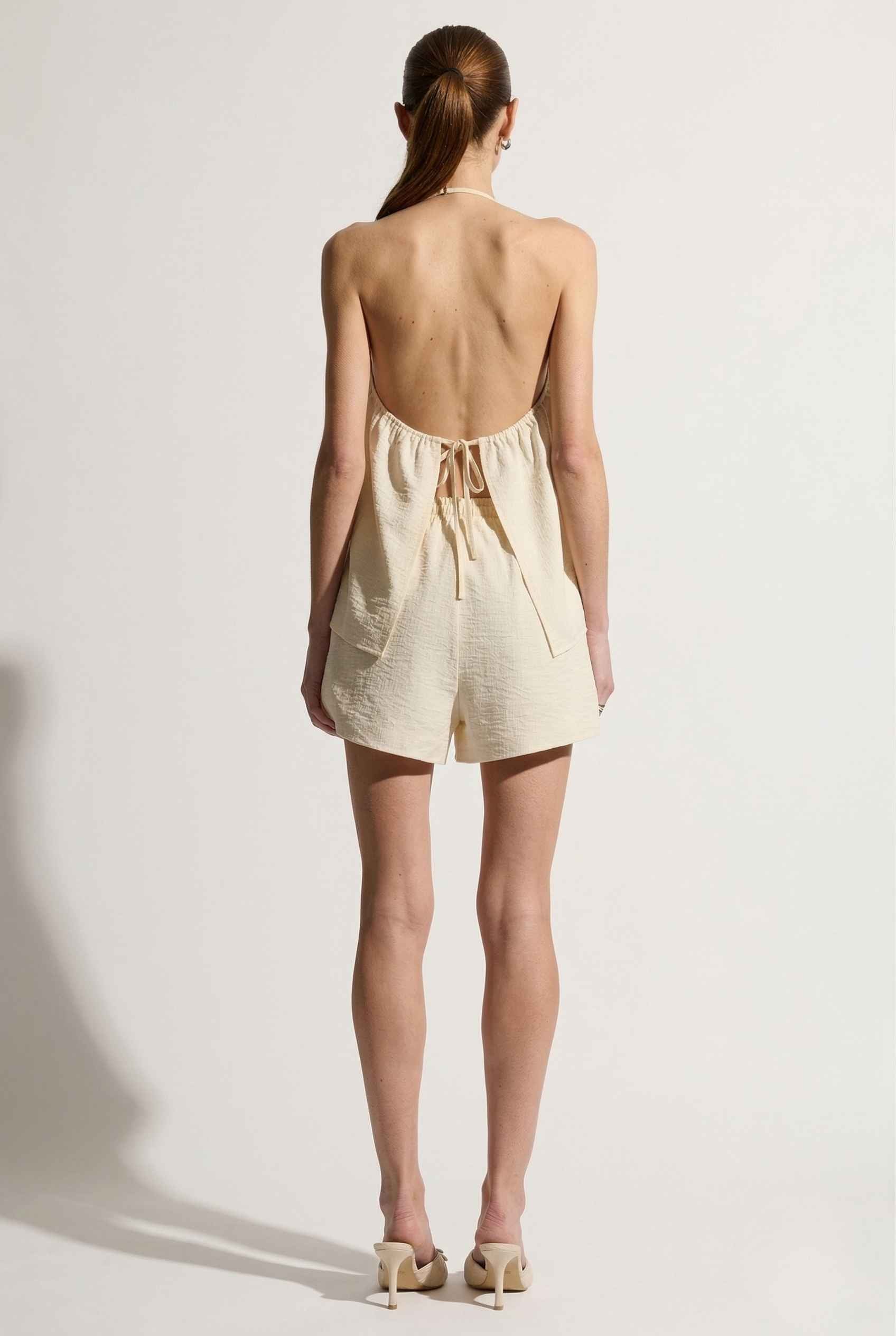 Woman wearing a Sienna Top Cream Tie-Front V-Neck Halter Tank on a white background