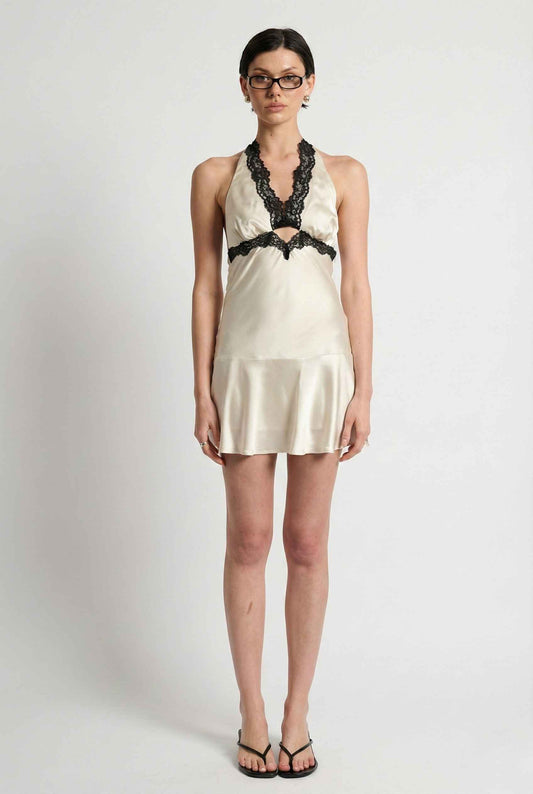 Woman wearing a Simone Mini Ivory Satin Halter Lace Trim Dress with black lace details on a white background