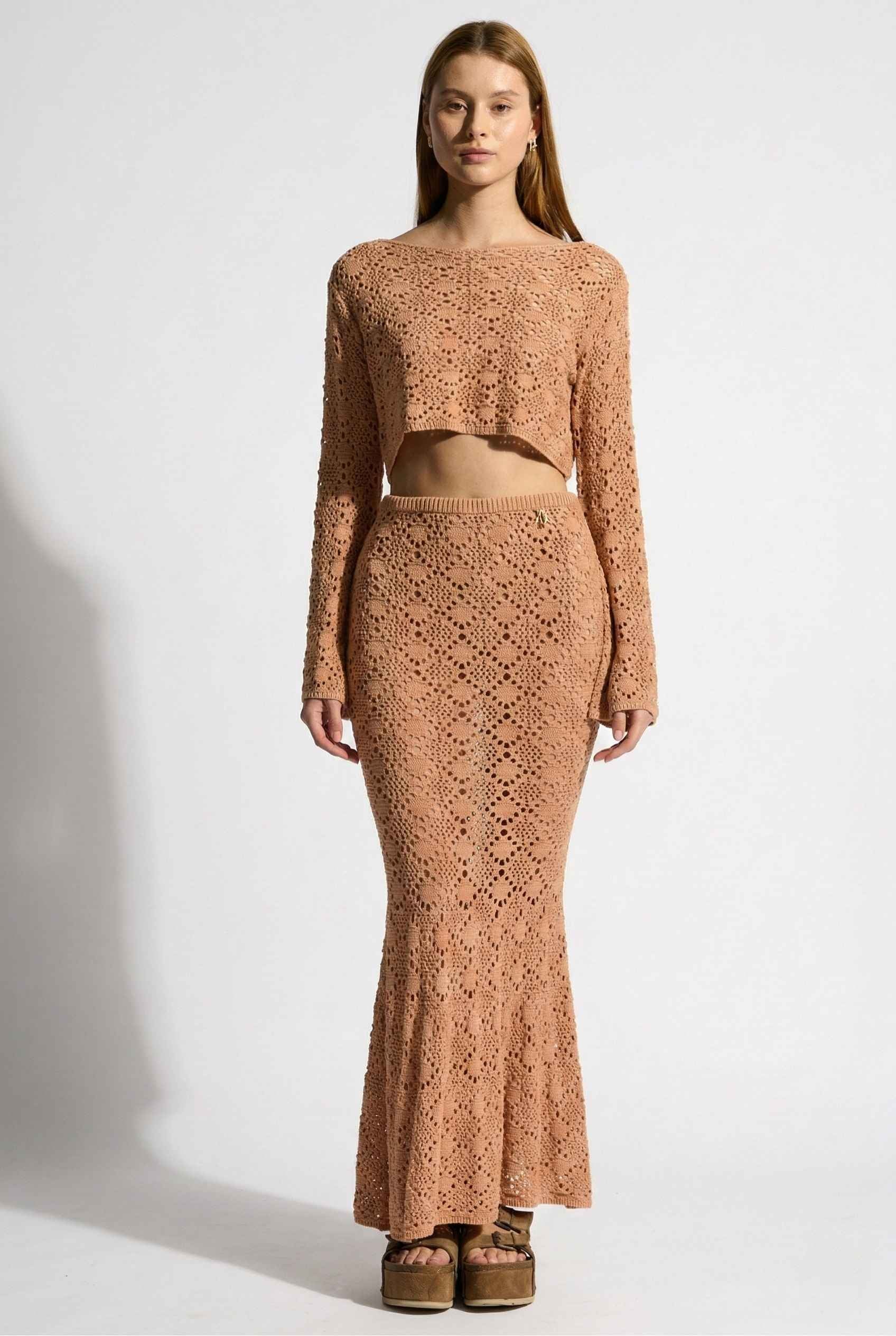 Model wearing Siren Skirt Open-Knit Crochet Mermaid Maxi Skirt in Camel Tan with matching crop top and platform sandals on plain background
