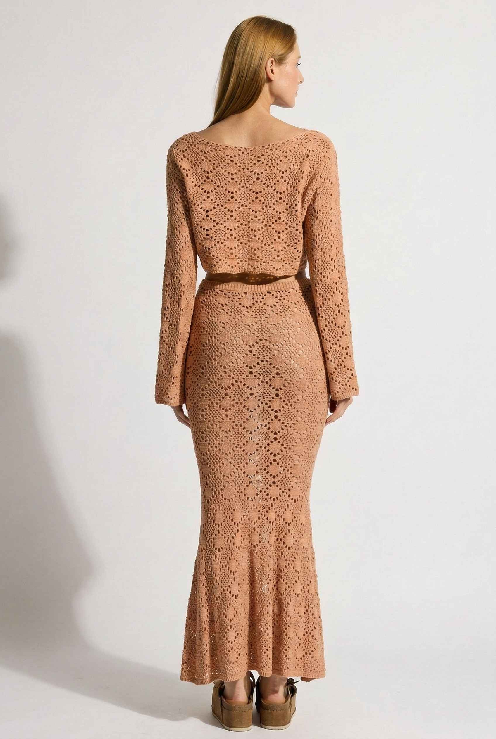 Model wearing Siren Skirt Open-Knit Crochet Mermaid Maxi Skirt in Camel Tan with matching crop top and platform sandals on plain background