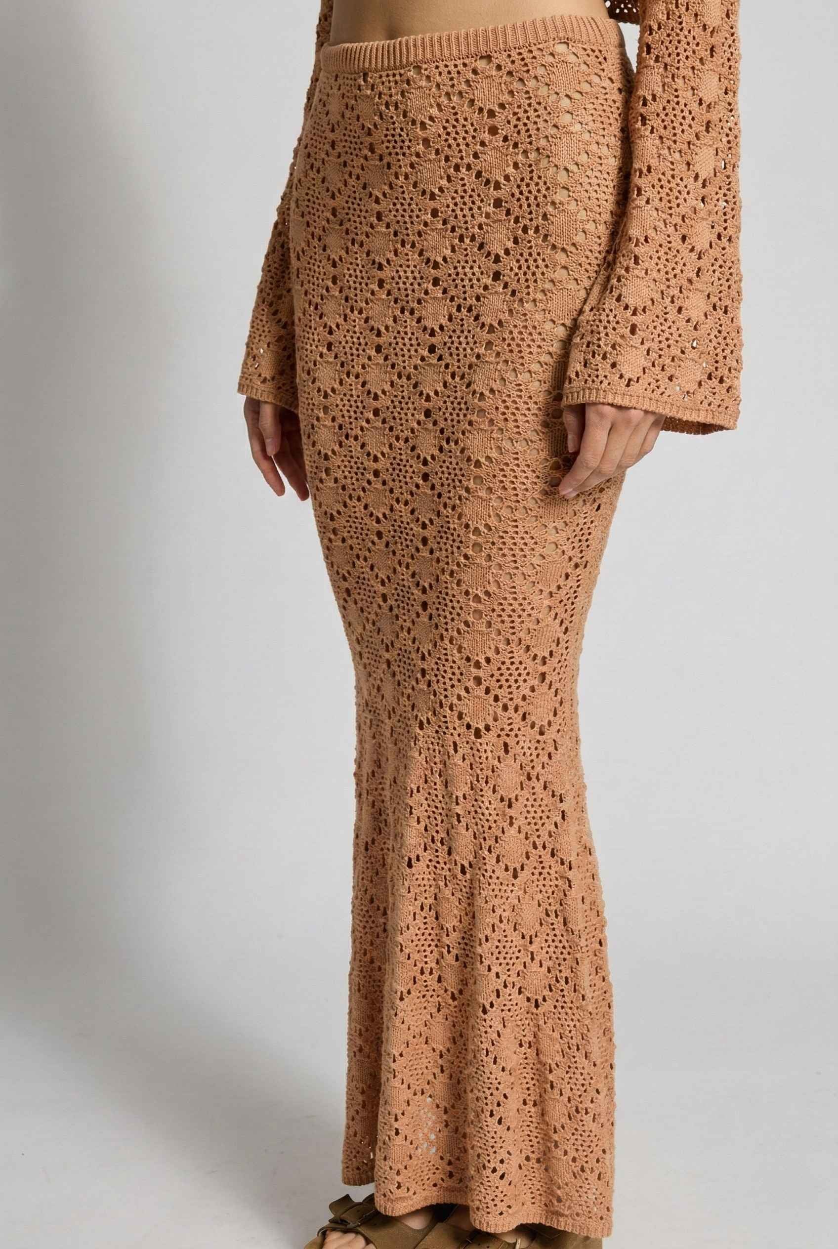 Model wearing Siren Skirt Open-Knit Crochet Mermaid Maxi Skirt in Camel Tan with matching crop top and platform sandals on plain background