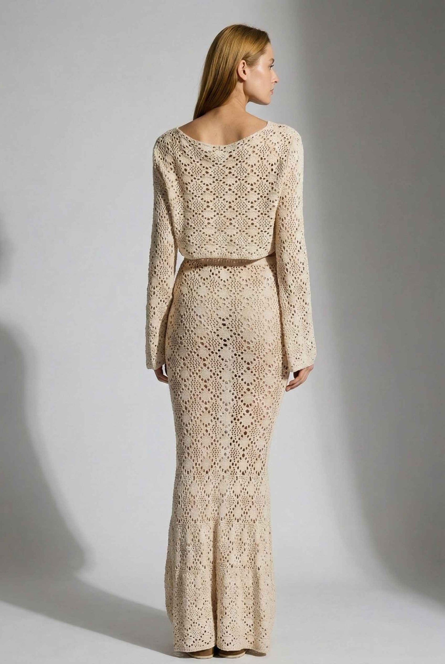 Model wearing Siren Skirt Open-Knit Crochet Mermaid Maxi Skirt in Sand Cream with matching crop top and platform sandals on plain background