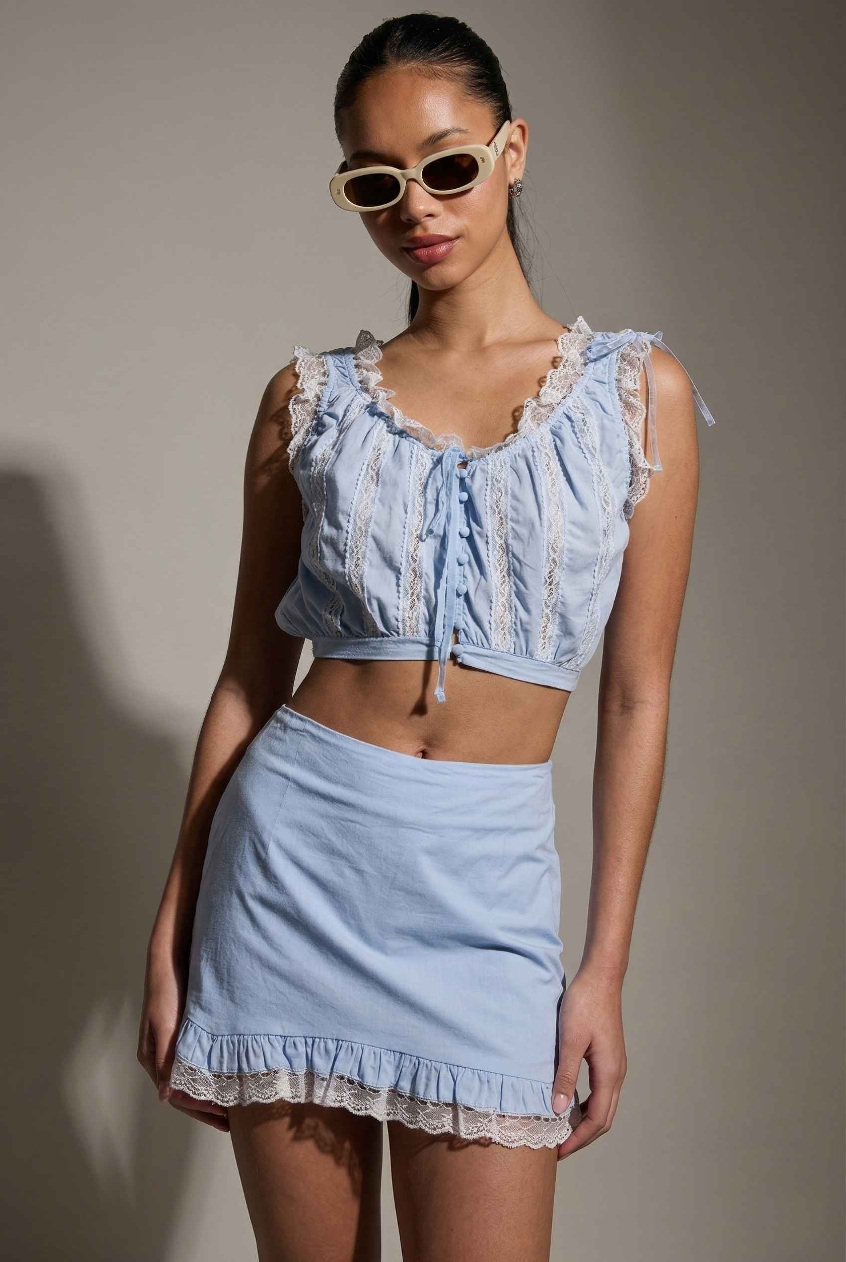 Model wearing Skye Skirt in Light Blue Cotton Mini Skirt with Delicate Lace Trim paired with matching top close up cotton detail