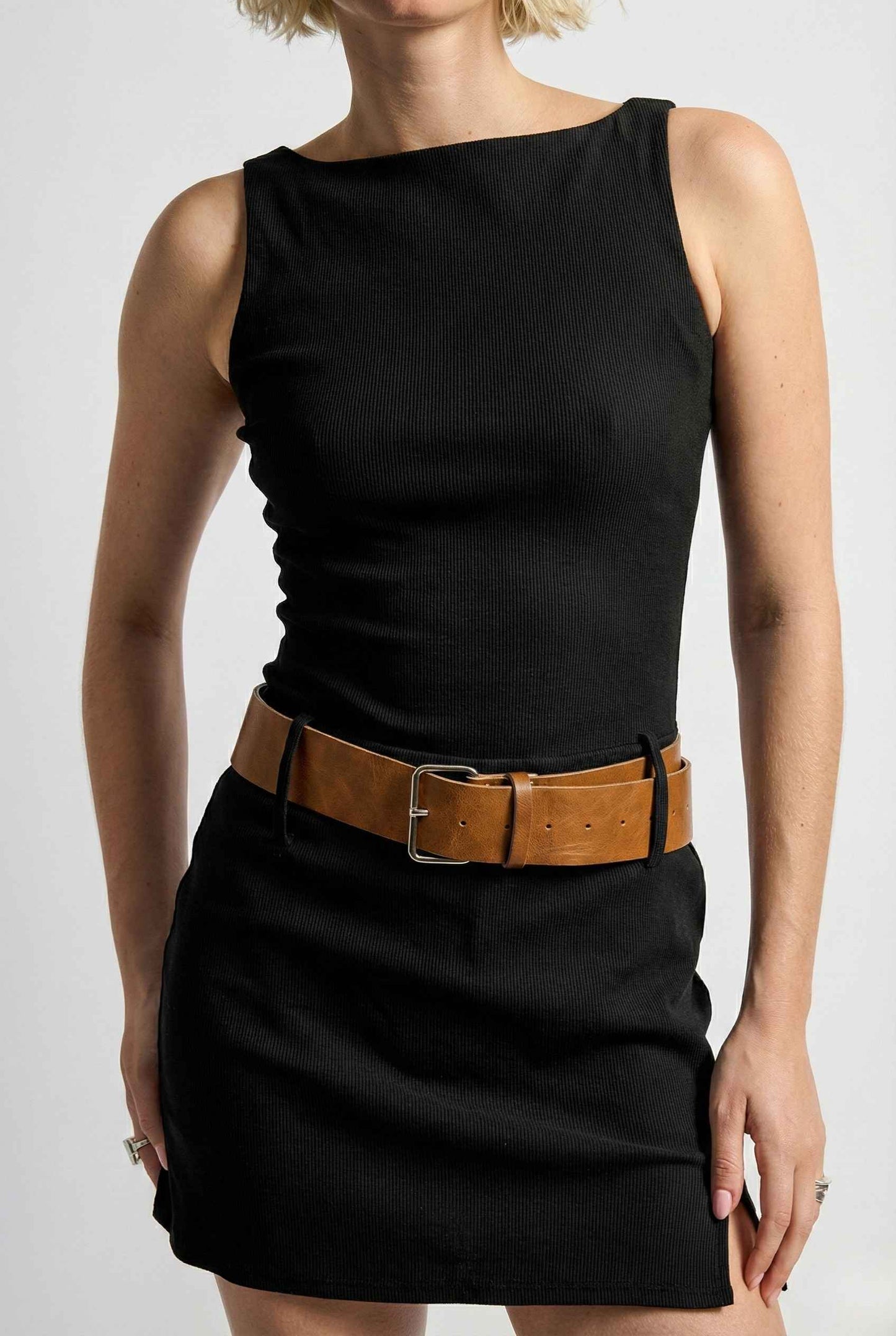 Person wearing a Sloane Mini Black Boat Neck Structured Knit Dress with a brown belt on a white background