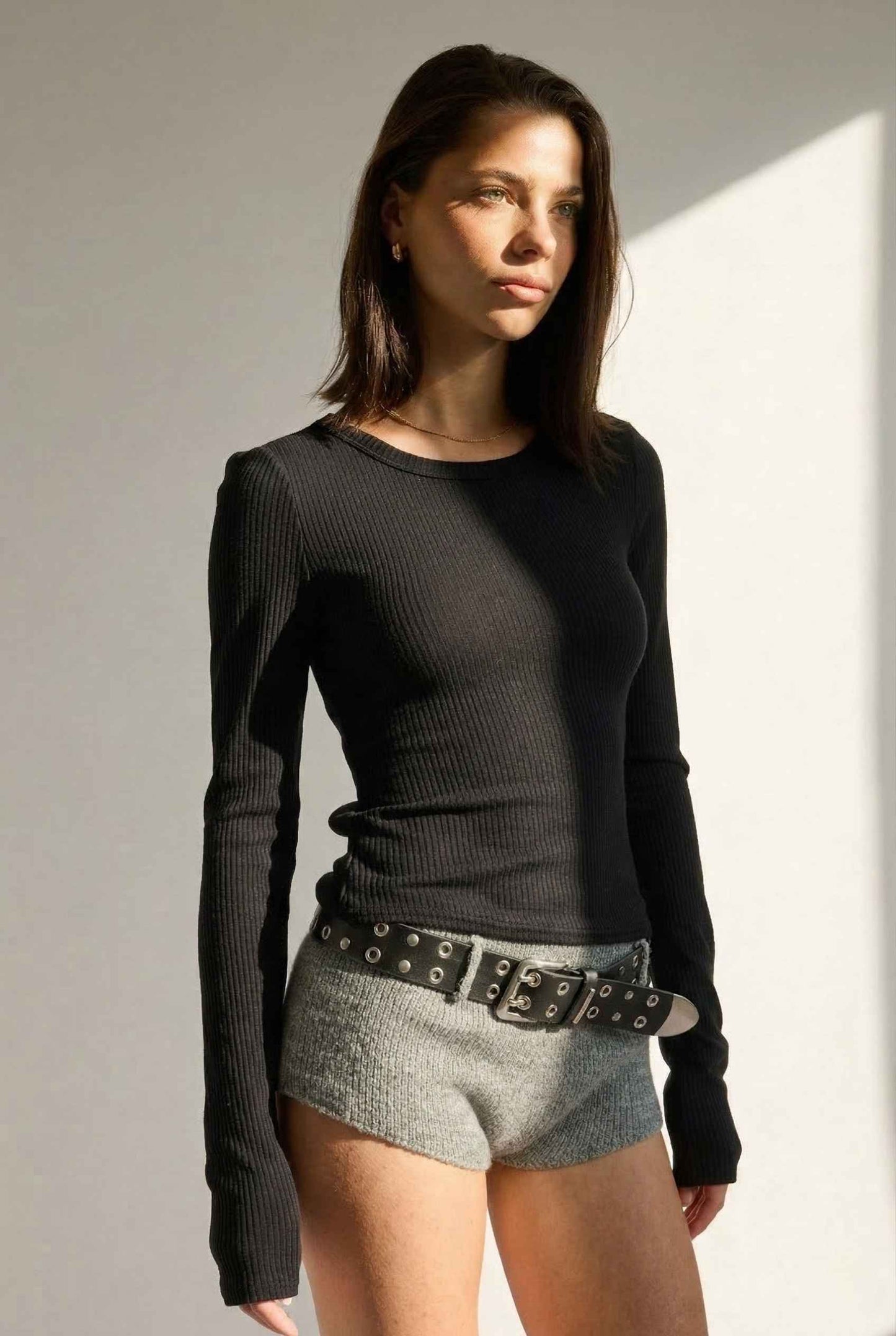 Model wearing Sloane Top in Black Cotton-Rayon Ribbed Crew Neck Long Sleeve Tee with knit shorts and belt