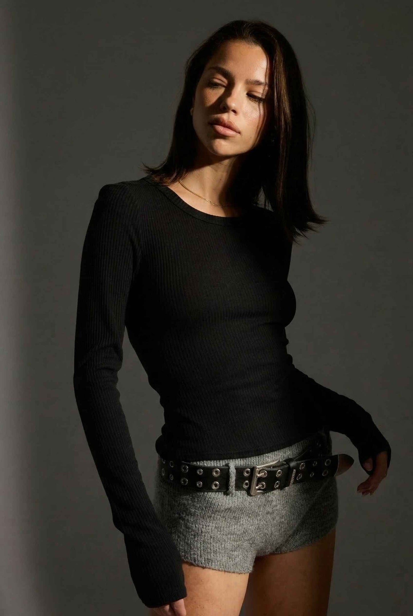 Model wearing Sloane Top in Black Cotton-Rayon Ribbed Crew Neck Long Sleeve Tee with knit shorts and belt