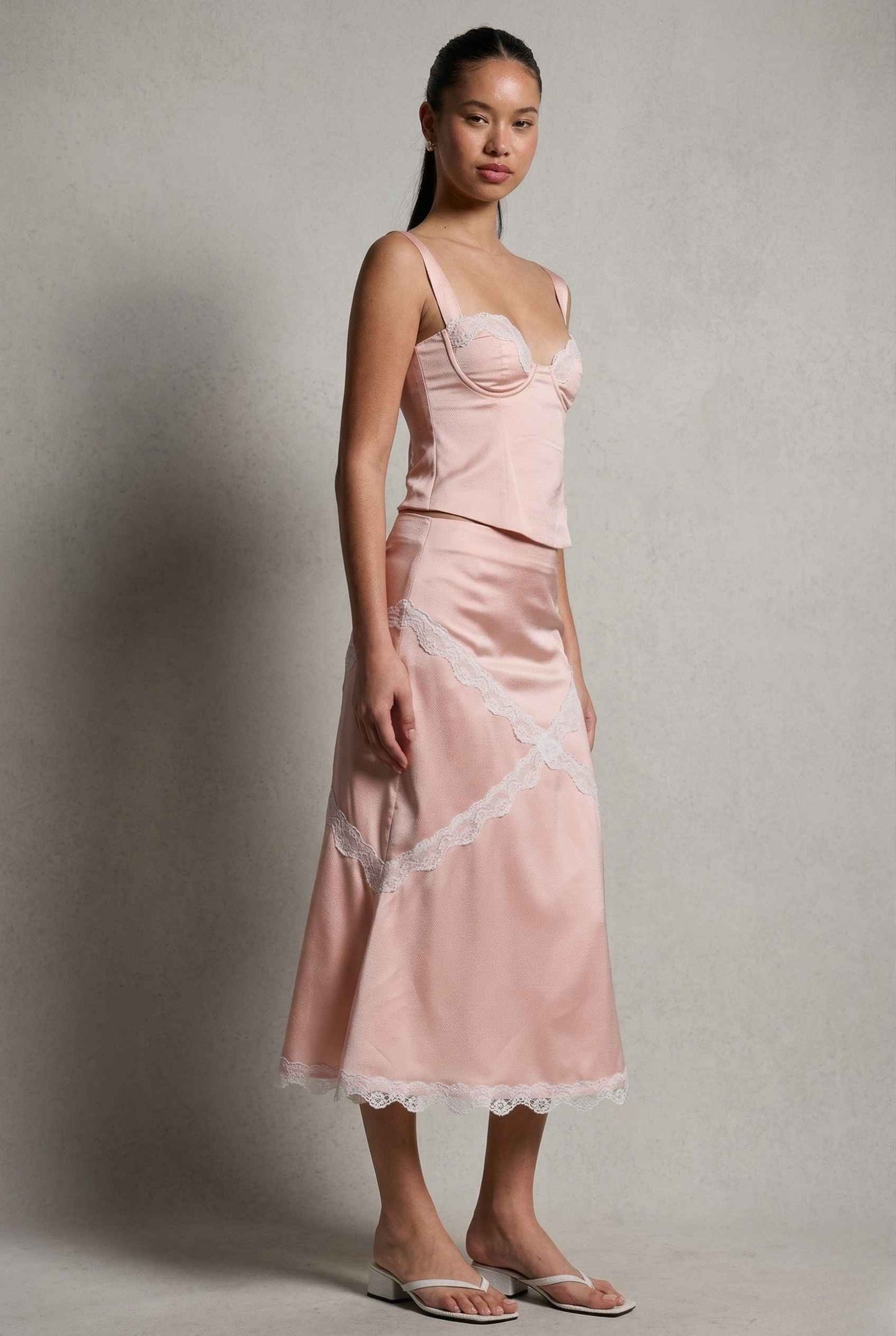 Woman wearing a Sophie Top Pink Pastel Satin Corset Cami with White Lace Trim with lace trim against a plain background